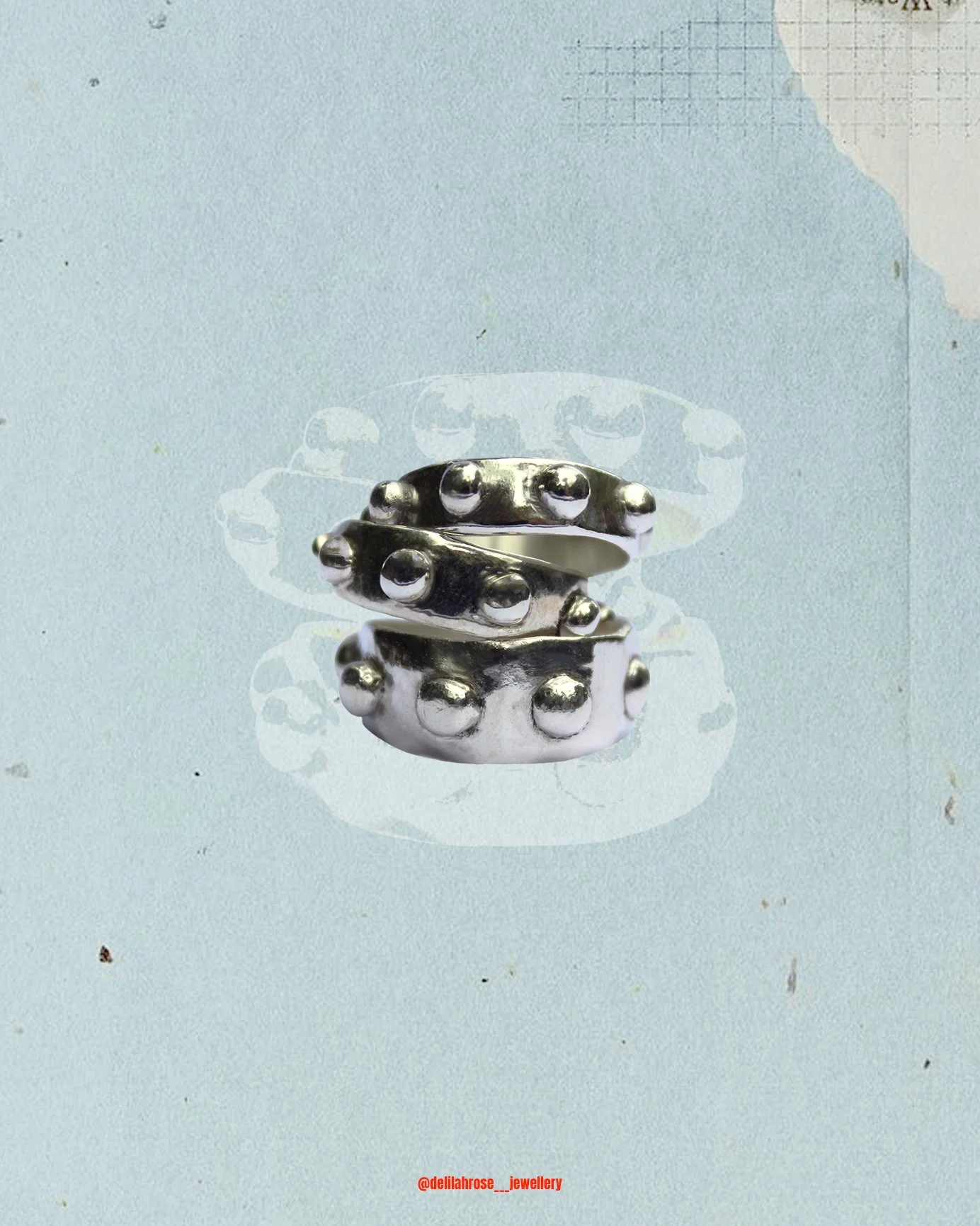 A 925 silver ring with rounded bumps, stacked over each other, on a textured light blue background with a faint white circular design. This is the bobble ring.