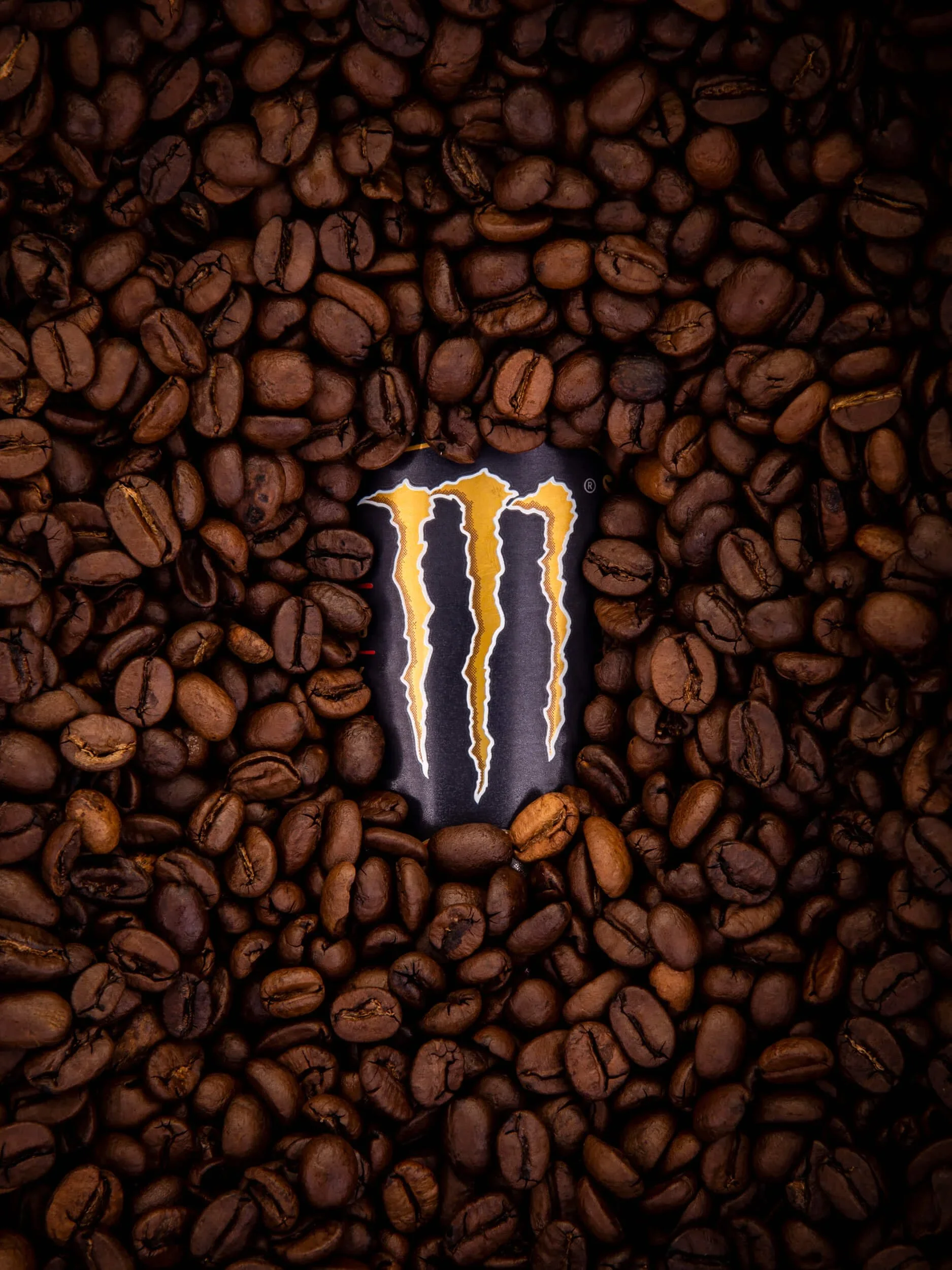 Koffiebonen met een Monster Energy logo er tussen.