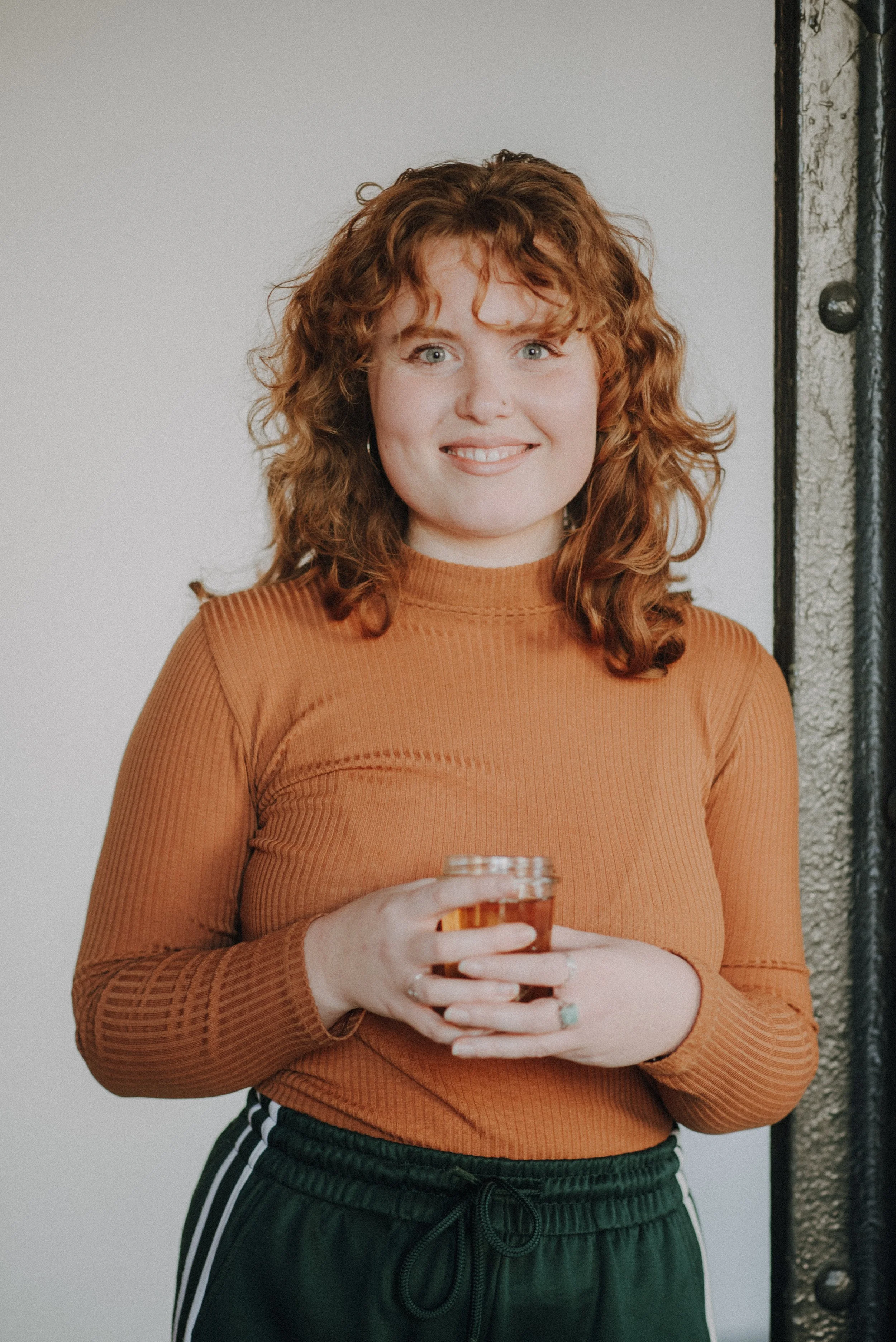 Schwarz-weiß-Fotografie unserer Trainerin Carina mit lockigem Haar, im Freien vor einer Berglandschaft.