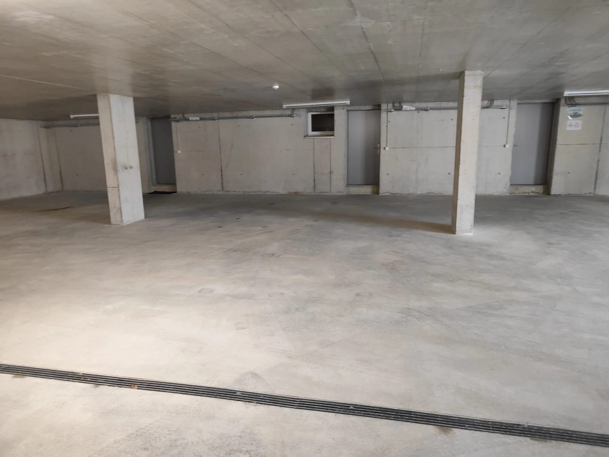 Leerer, unbelegter Parkraum in einem mehrstöckigen Parkhaus mit Betonwänden, -säulen und –boden.