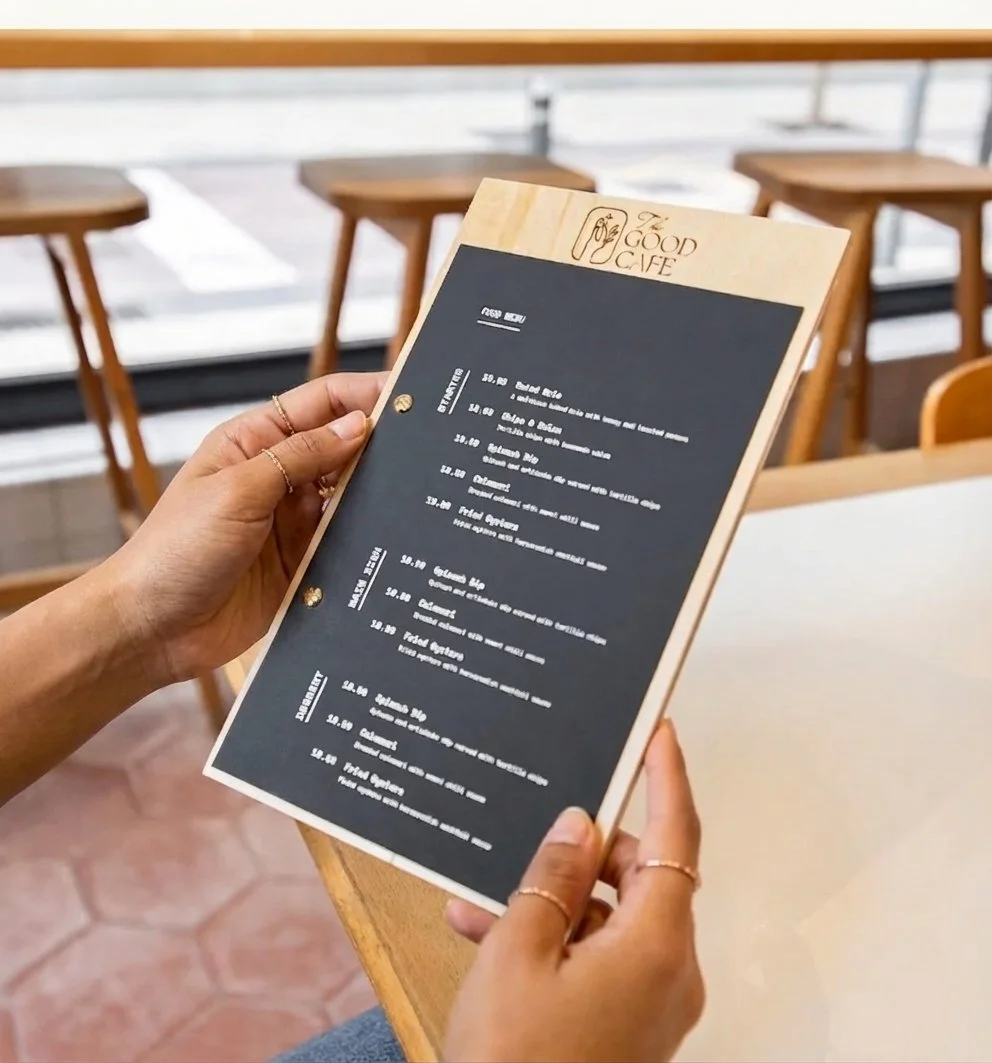 Custom wooden menu board with printed menu insert being held in a café setting