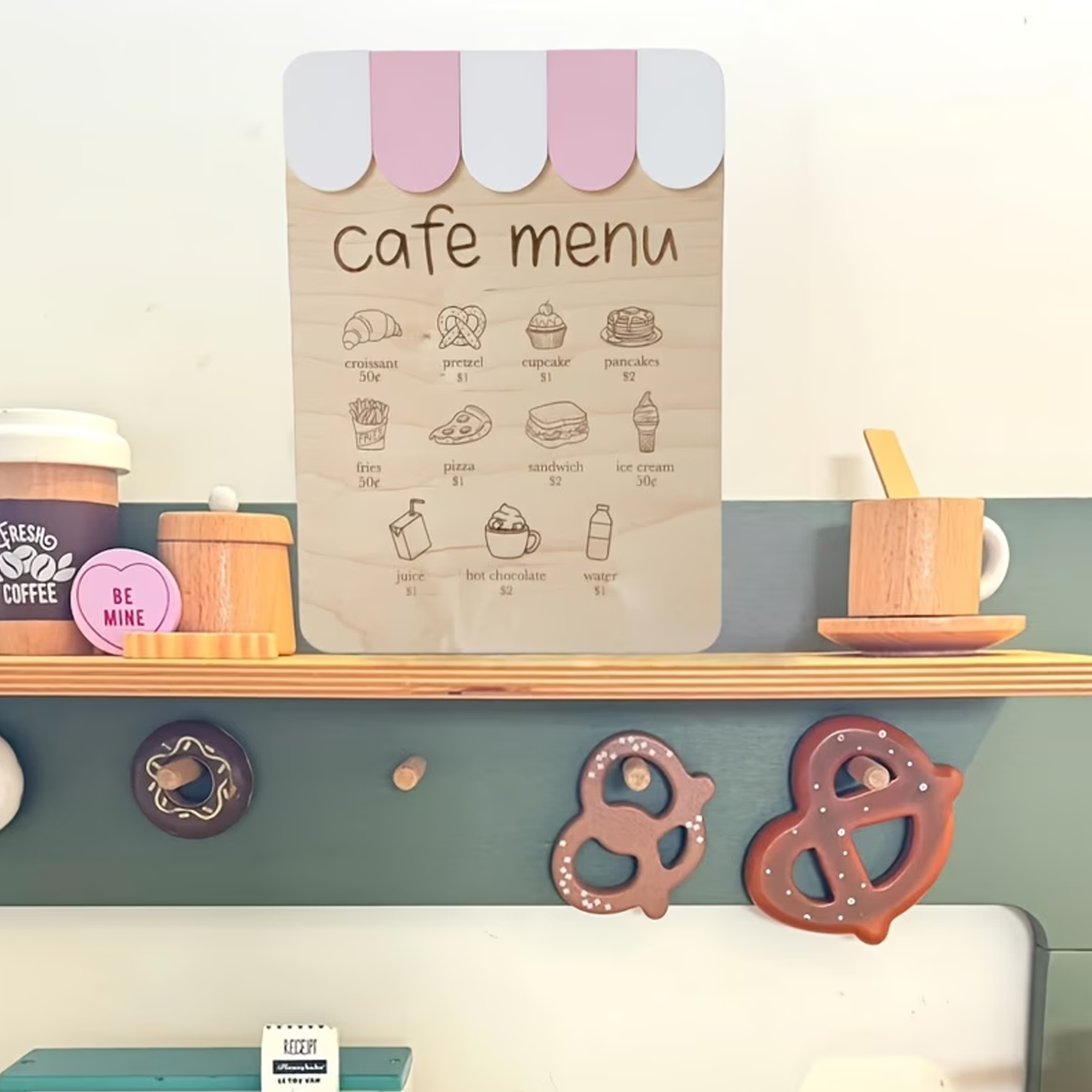 Cute cafe menu board featuring illustrated baked goods and beverages with their prices, and decorative pretzels hanging below.
