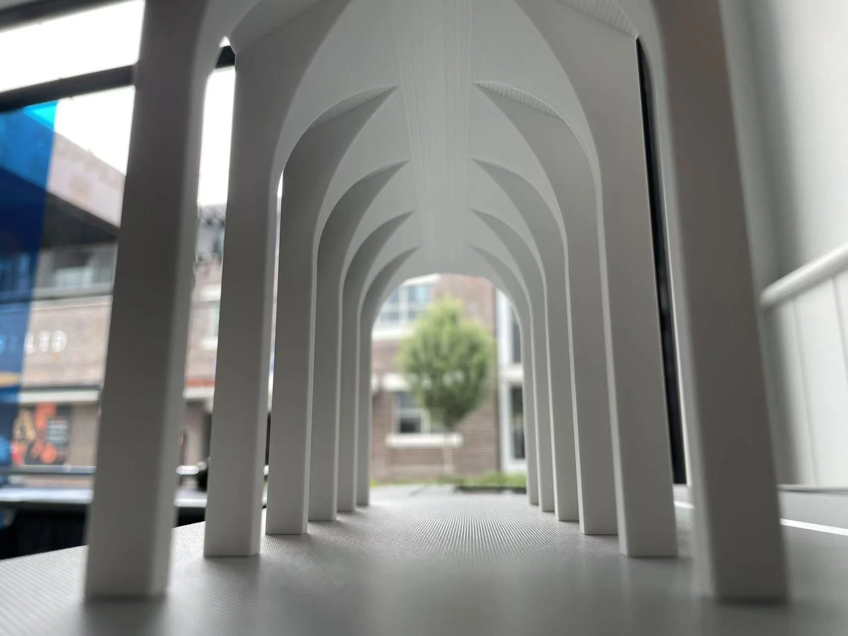 Close-up view through a white architectural model showing repeated arched structural elements and interior depth