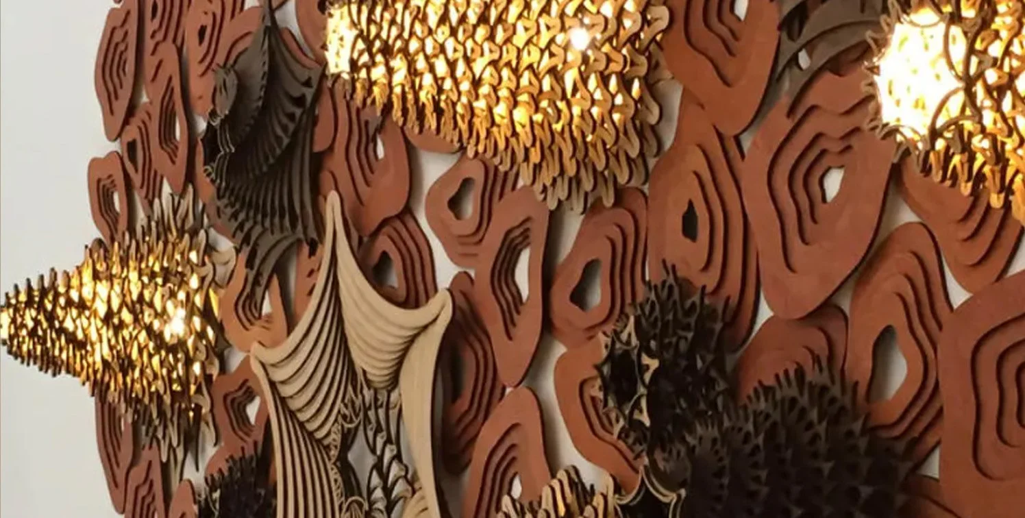 Intricate laser-cut ceiling installation featuring layered organic patterns and sculptural pendant lights with warm illumination.