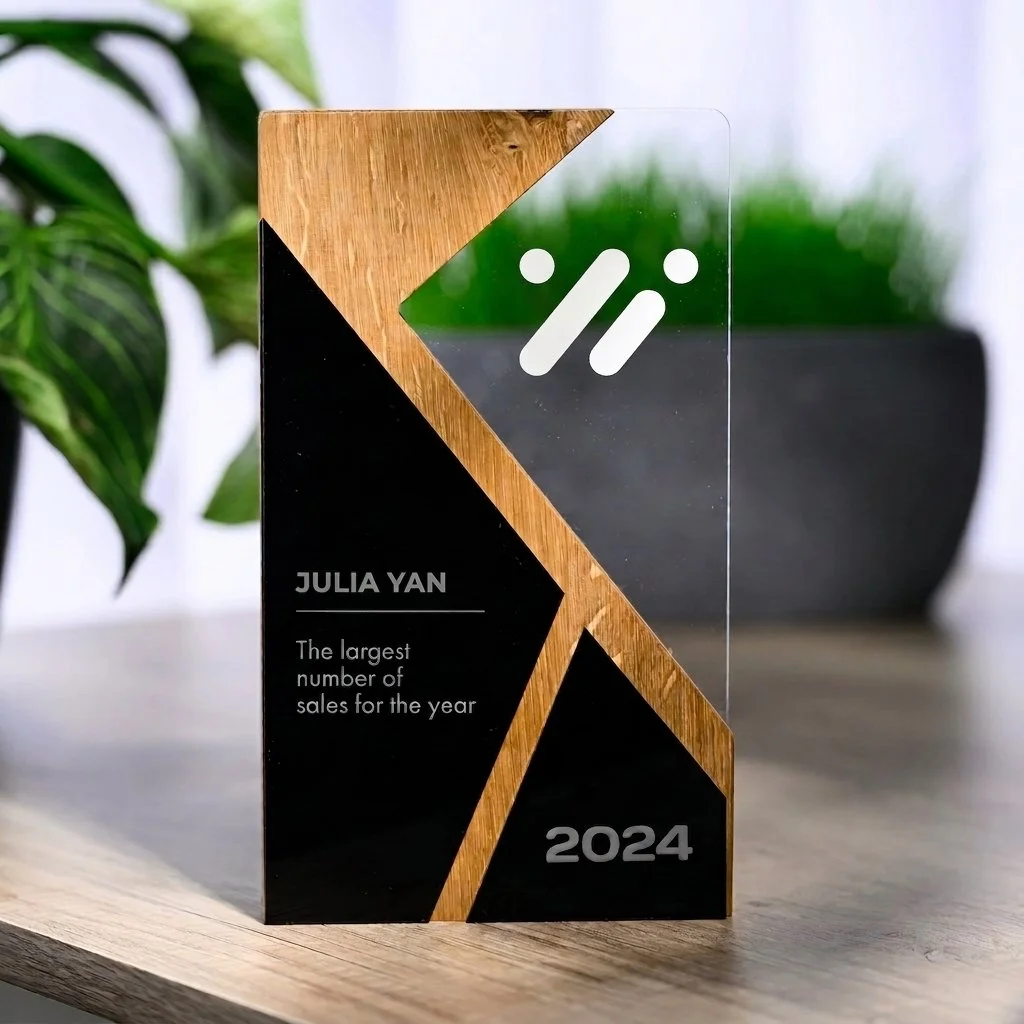 Freestanding acrylic and timber award with printed recognition text and geometric layered design displayed on a tabletop