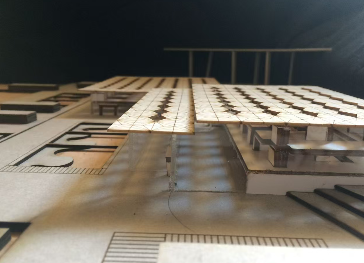 Close-up of an architectural model with laser-cut roof panels, engraved surface details, and layered structural elements.