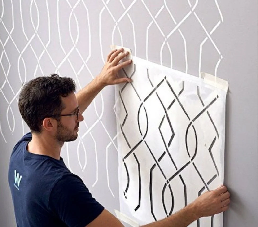 Reusable pattern wall stencil being positioned for a repeating geometric interior design