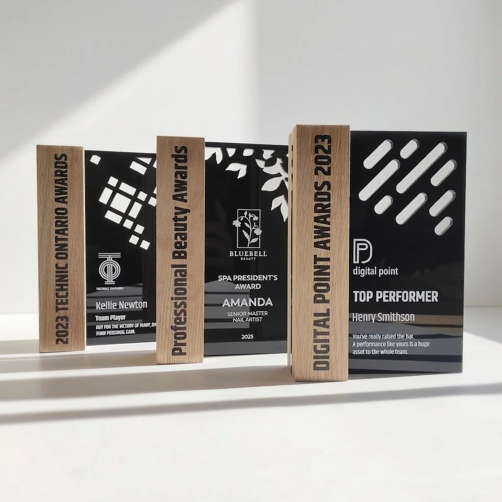 Custom freestanding awards in black acrylic and timber with engraved and printed recognition details displayed together