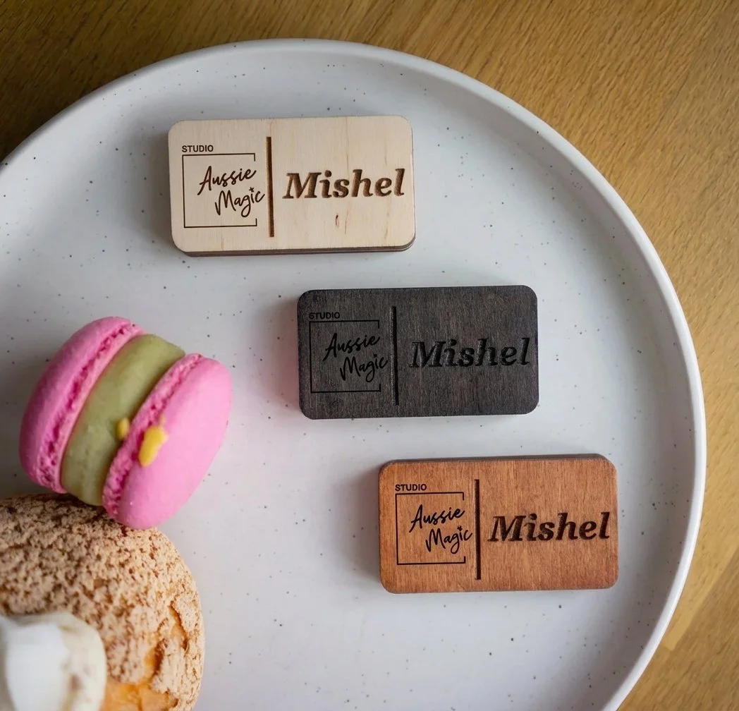 Custom wooden name badges in different finishes with engraved names and logo placed on a plate