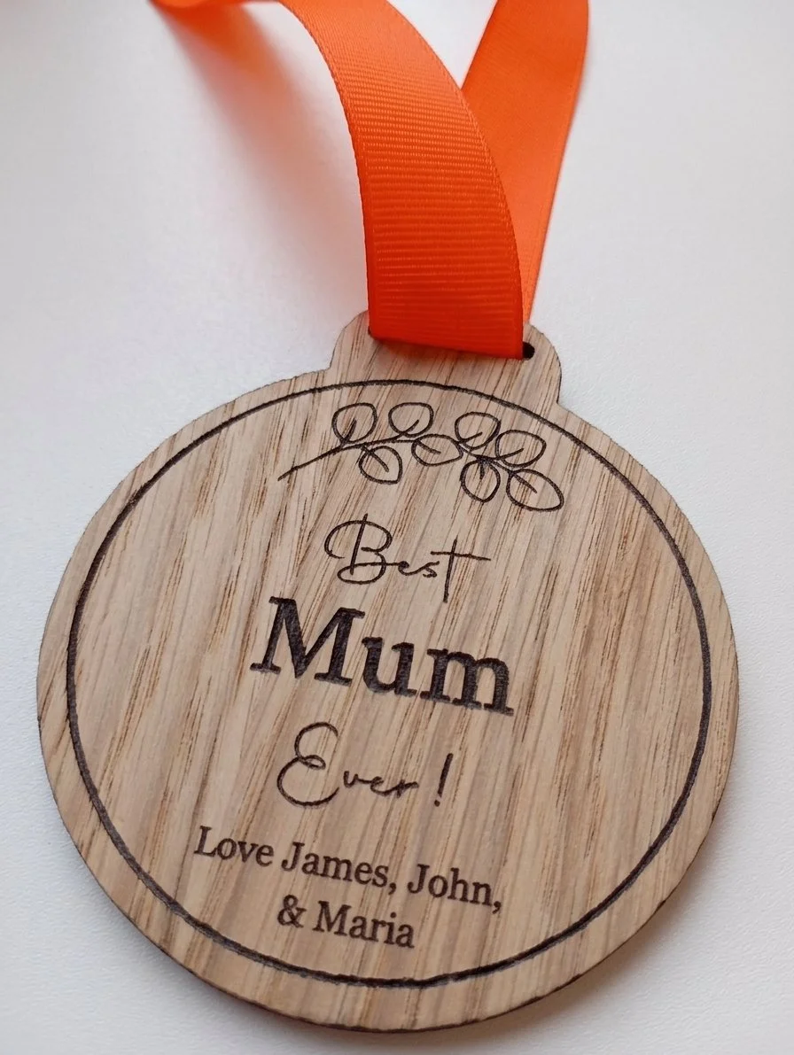 Round wooden medal with engraved personalised message and ribbon shown in close-up