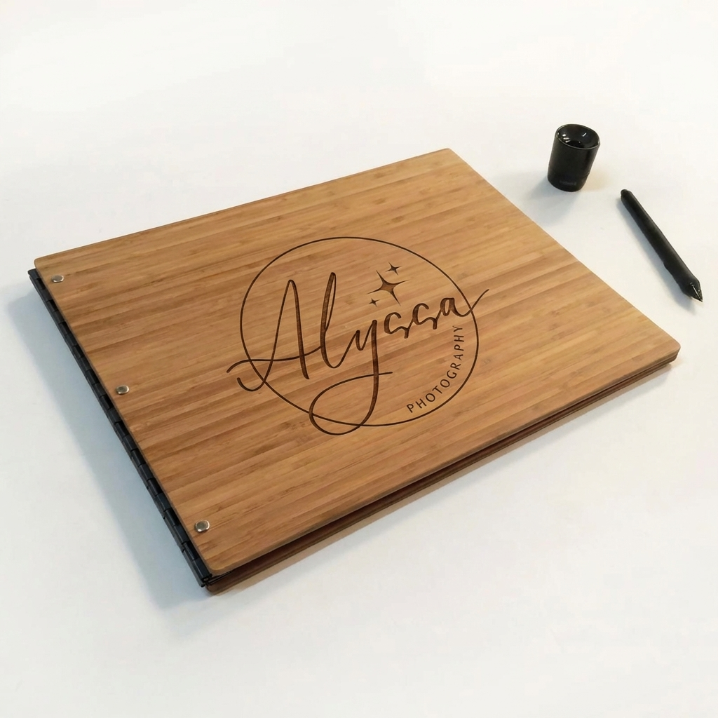 A wooden notebook cover with the name 'Alyssa' and the word 'Photography' engraved on it, accompanied by a black pen and a small black container on a white surface.