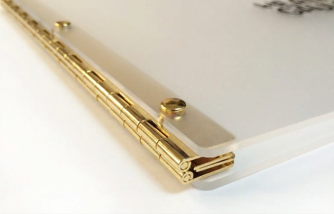 Close-up of a silver laptop with gold hinges.