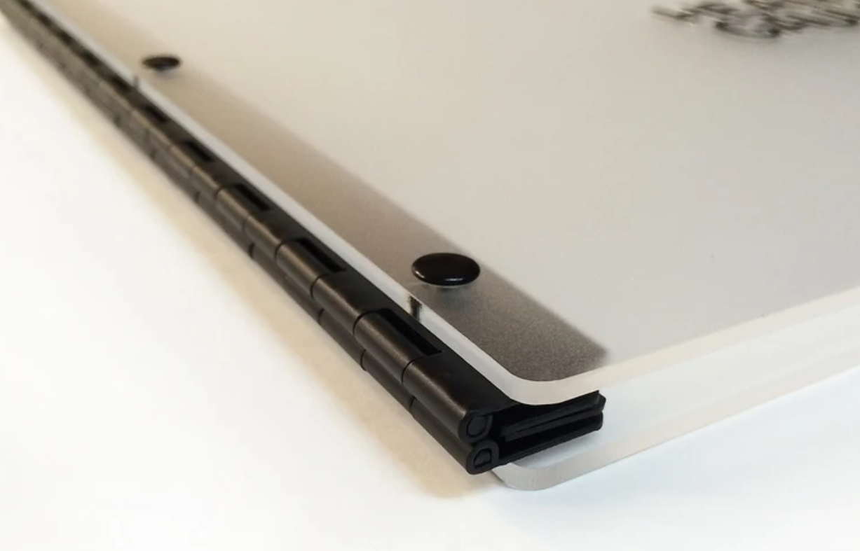 Close-up of the hinge on a silver laptop with the screen partially open, showing the hinge mechanism and a small black rubber foot.