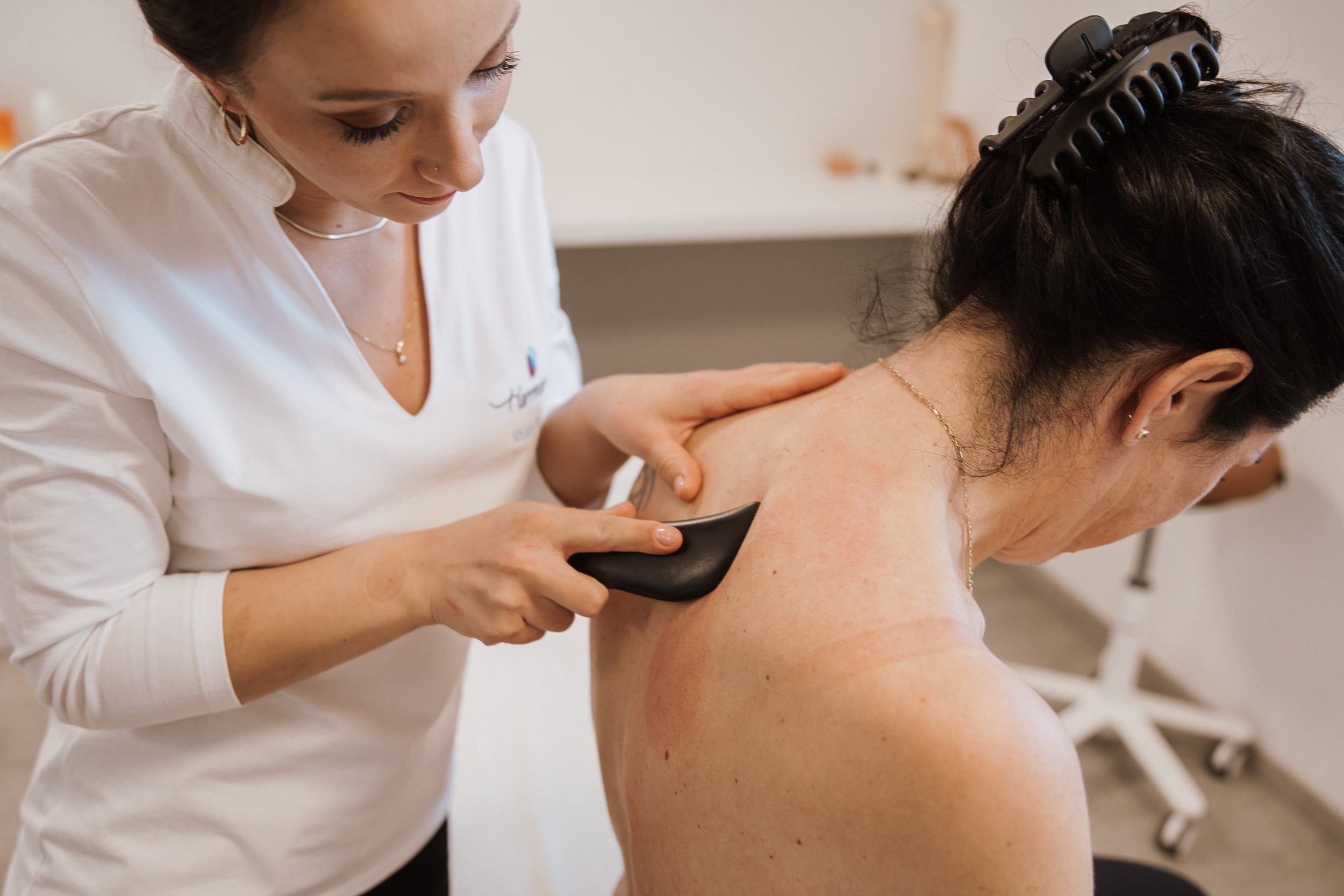 Ärztin behandelt Rücken einer Patientin mit einer Ultraschallsonde in einer Klinik.