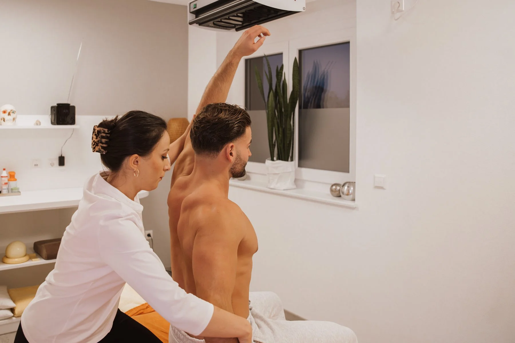 Ein Mann erhält eine Rückenmassage in einer Wellness- oder Physiotherapiepraxis während eine Therapeutin ihn behandelt.