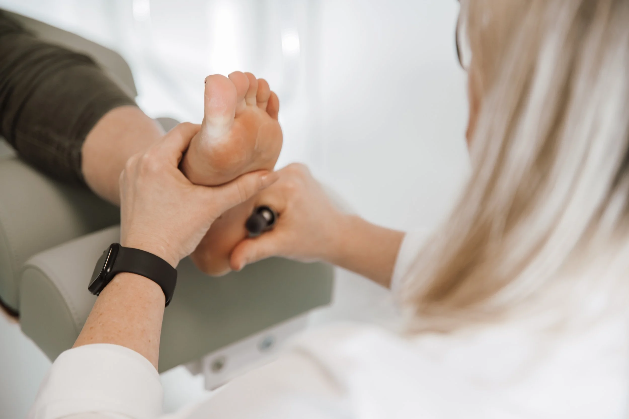 Pflegekraft hält die Hand einer älteren Person während der Behandlung in einem Pflegeheim oder Krankenhaus.