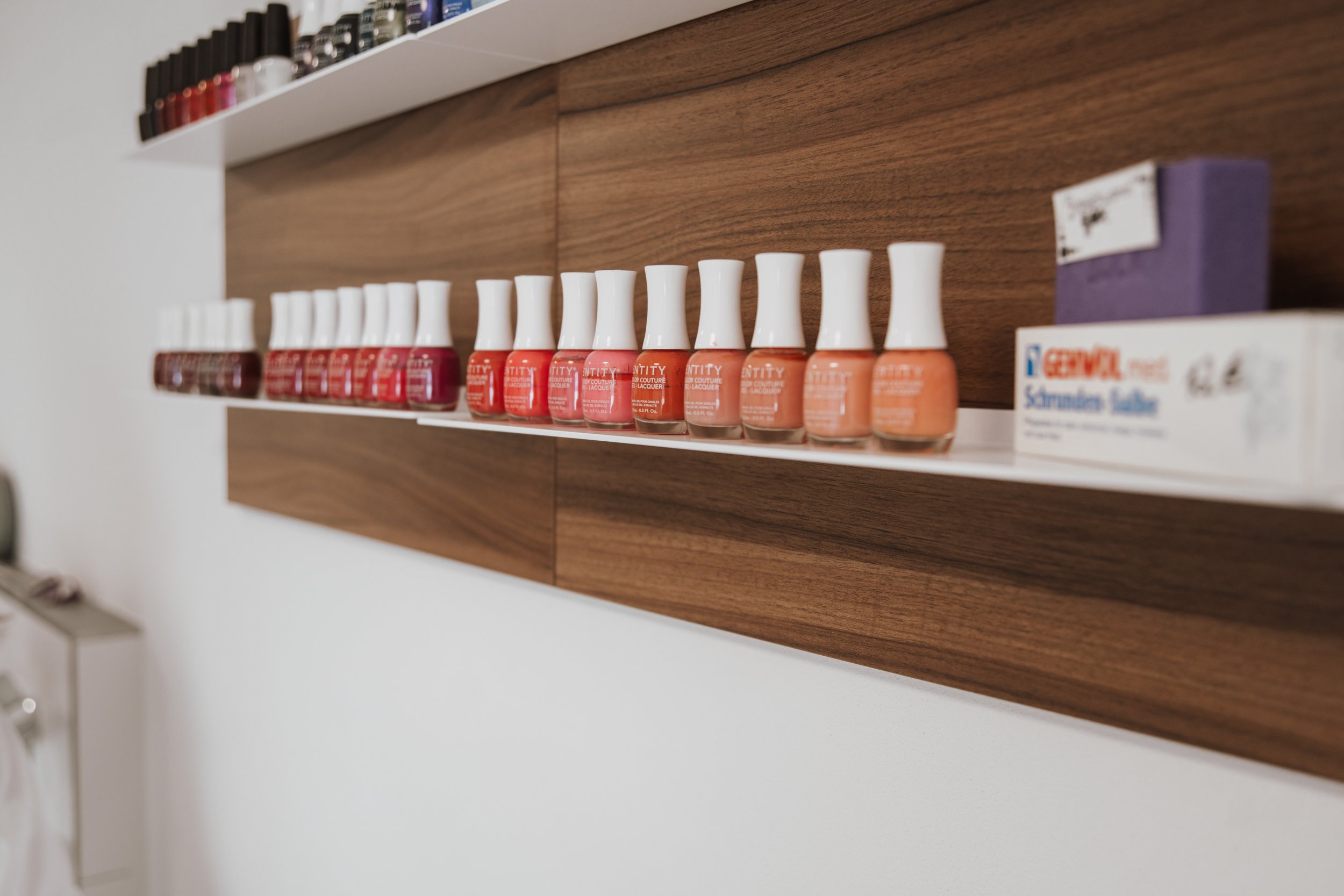 Nagellack in verschiedenen Rot- und Orangetönen auf einer Wandregal in einem Raum