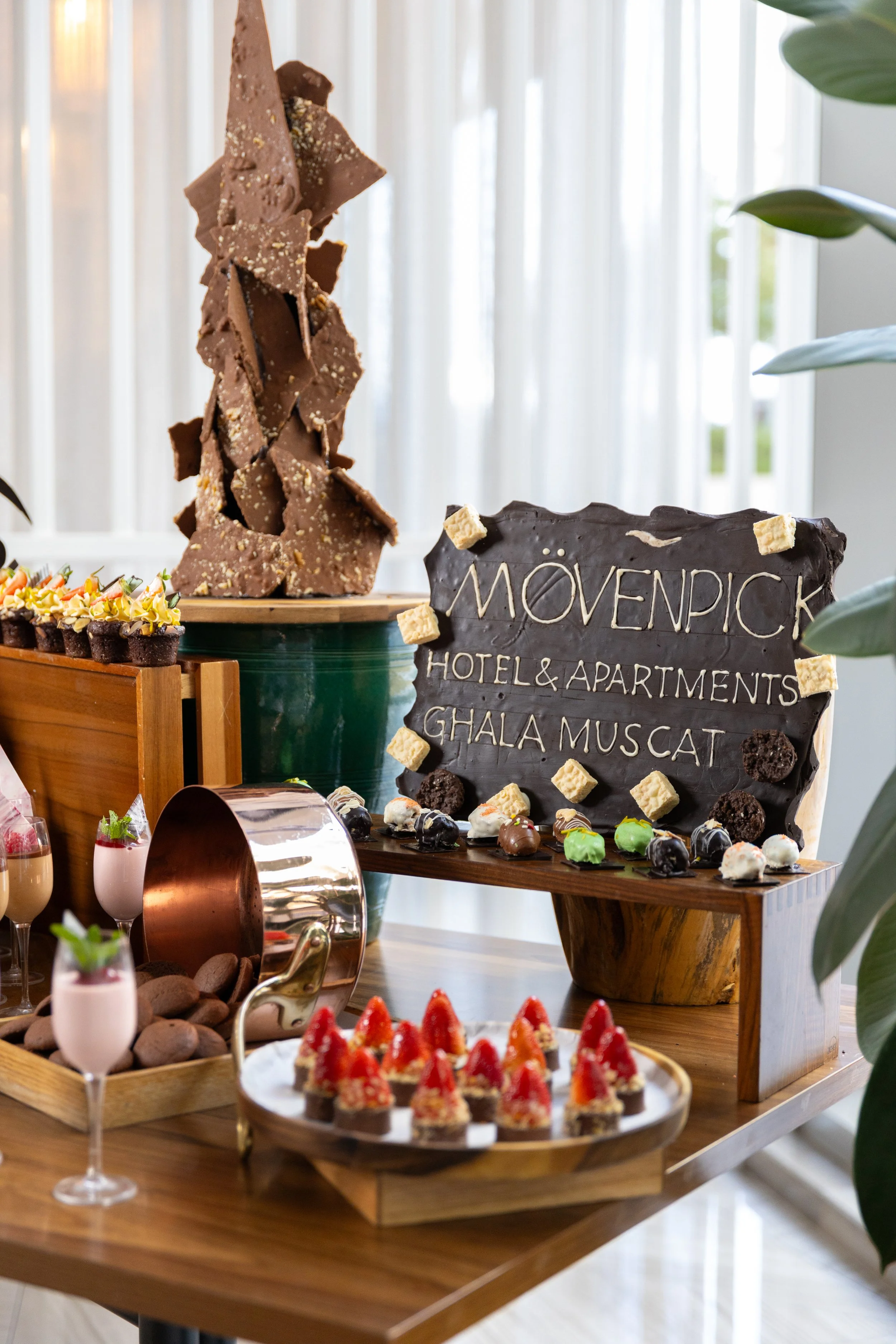 A landscape with rolling green hills in the foreground, a modern building on the hillside, and snow-capped mountains in the background under a cloudy sky.