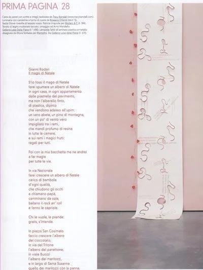 A magazine page with Italian text on the left side and a long strip of paper with cursive writing along the right side.