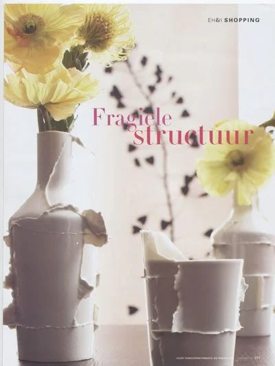 Broken white vases with yellow flowers on a table
