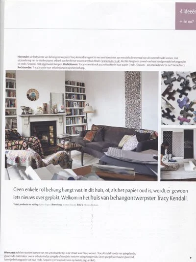 Living room with a fireplace, bookshelves, sofas, armchairs, coffee table, and a puzzle on the wall.