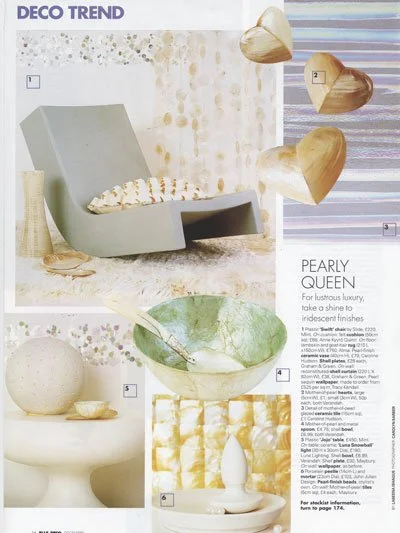Decor magazine page featuring images of modern furniture and decor items, including a gray armchair with a pillow, hanging wooden wall art, a spherical lamp, a decorative bowl with a spoon, and a small vase.