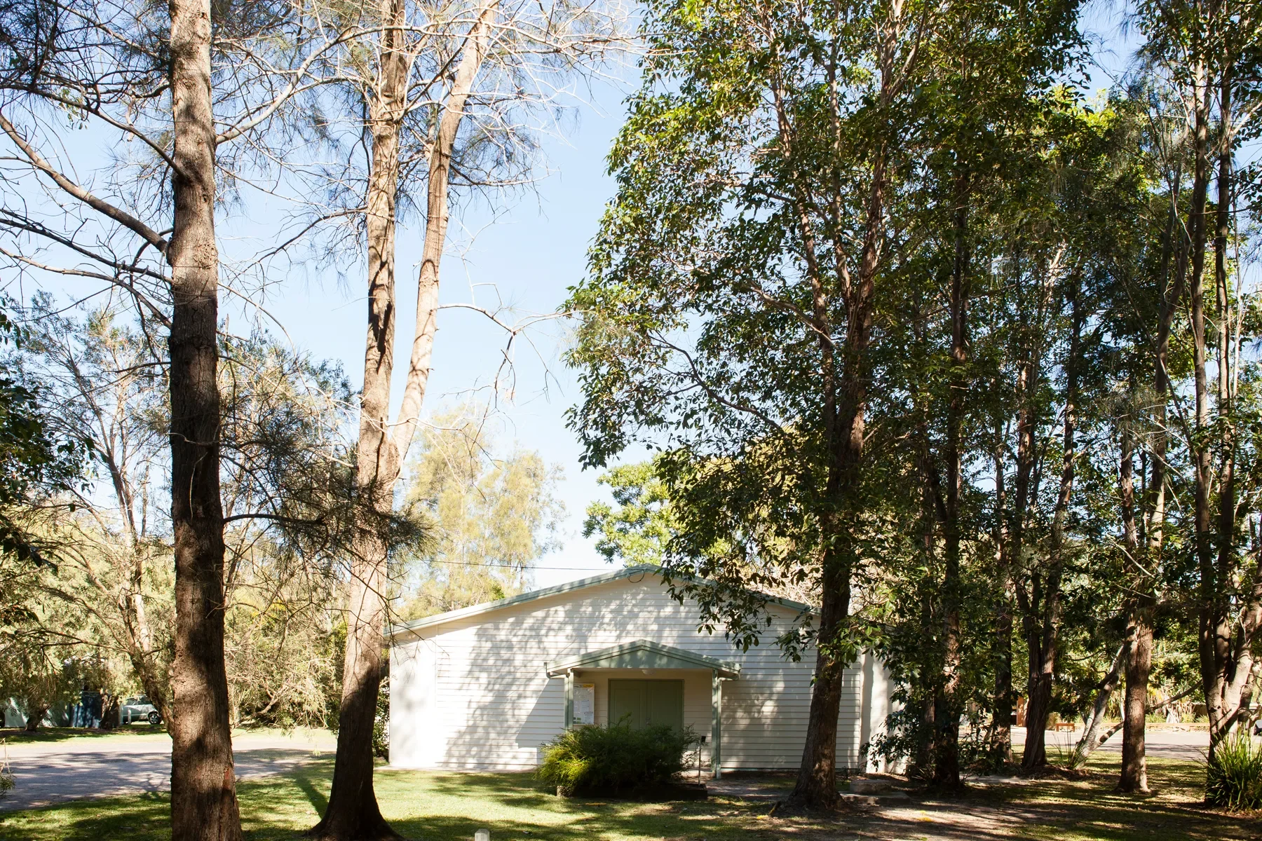 A white building surrounded by trees and grass under a clear blue sky.