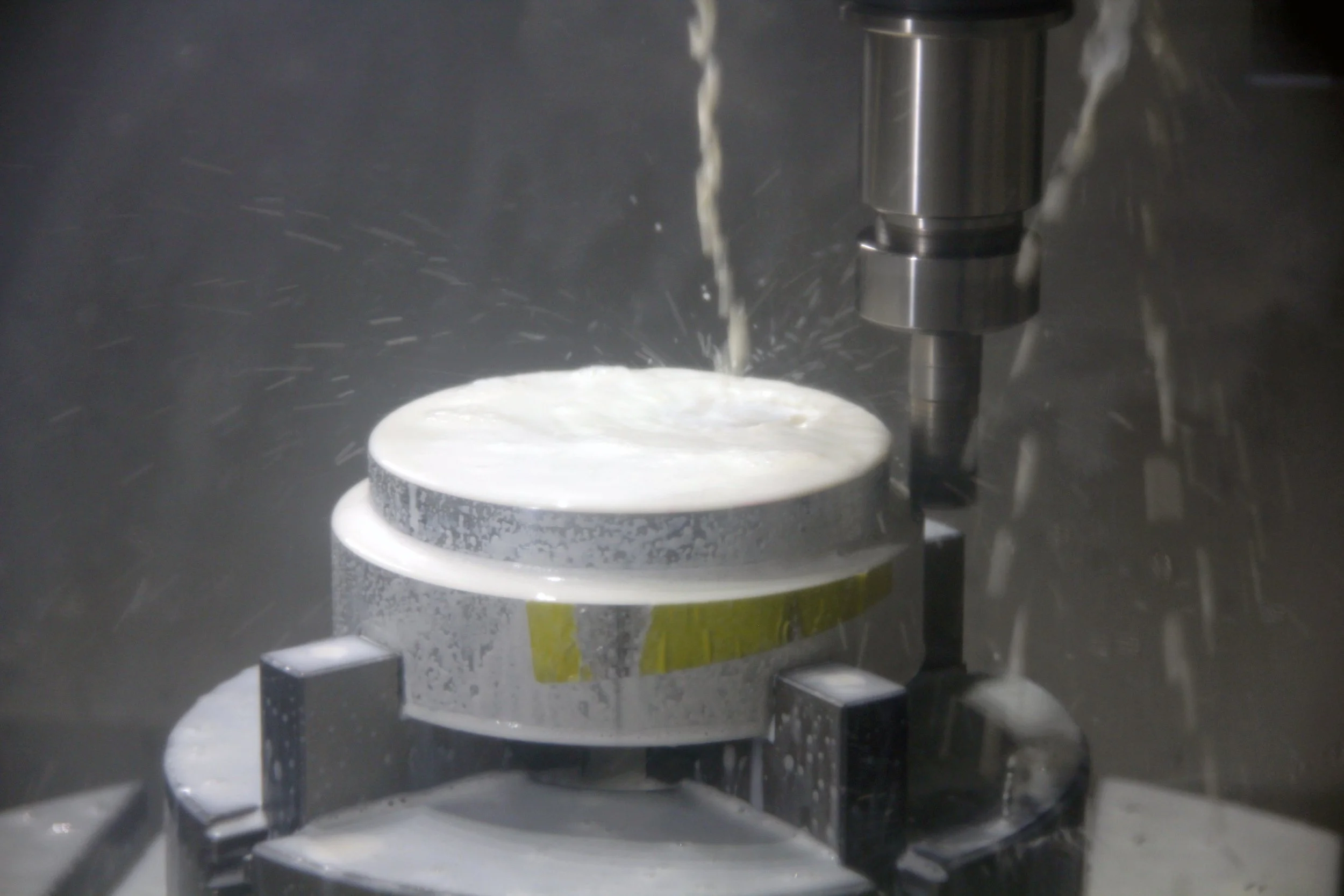 Fresatura di un particolare meccanico in una macchina a 5 assi con fresa in funzionamento.