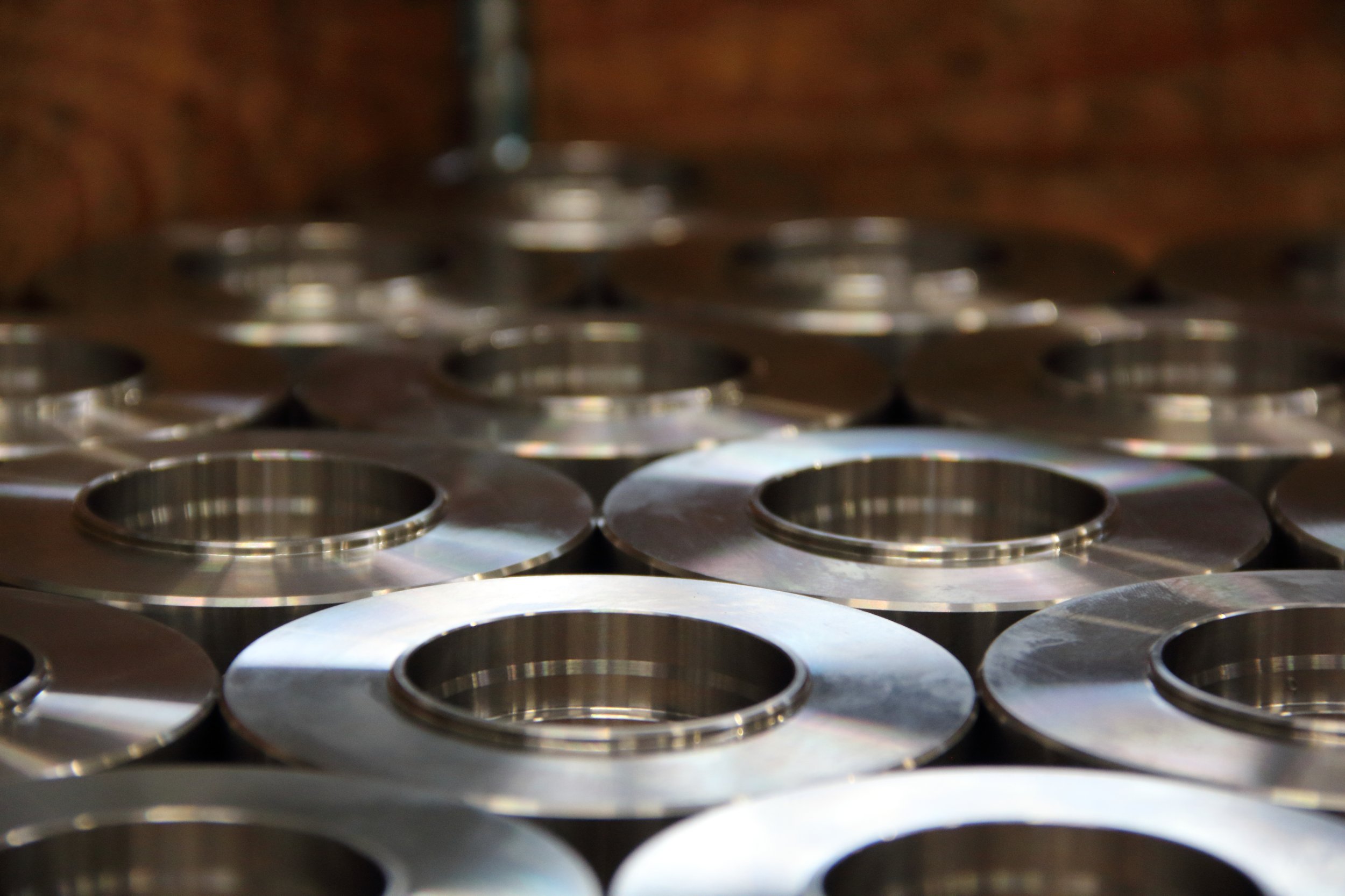 Serie di particolari meccanici torniti in acciaio stoccati in cassa.