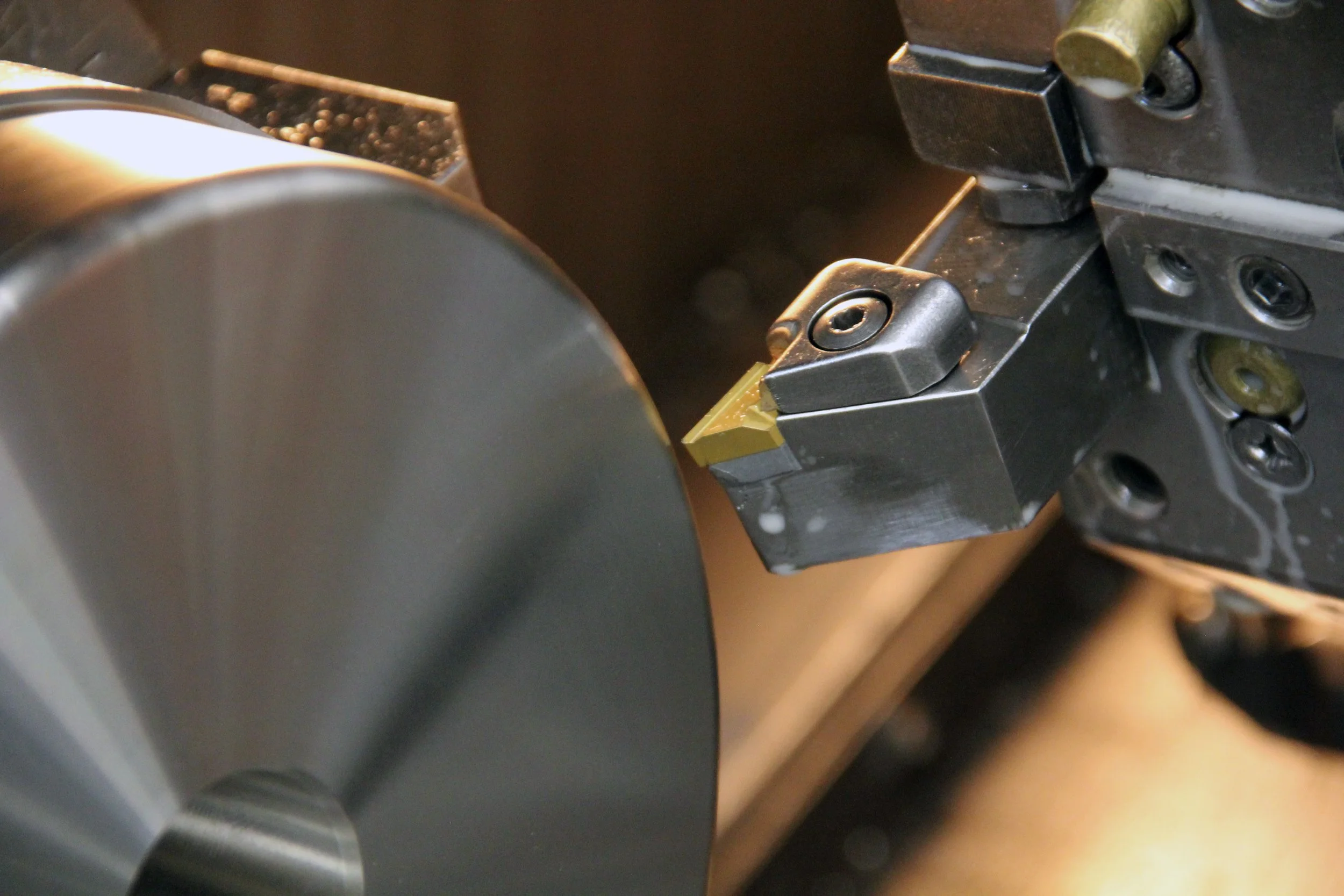 Tornitura di un particolare meccanico su tornio tramite un utensile e inserto per metallo.