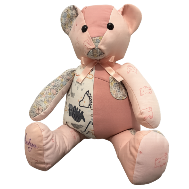 A plush teddy bear with a patchwork design, including pink, beige, and patterned fabric, with black button eyes and a stitched nose.