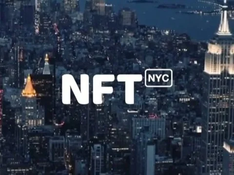 Sfondo della skyline di New York di notte con testo 'NFT NYC' in primo piano.