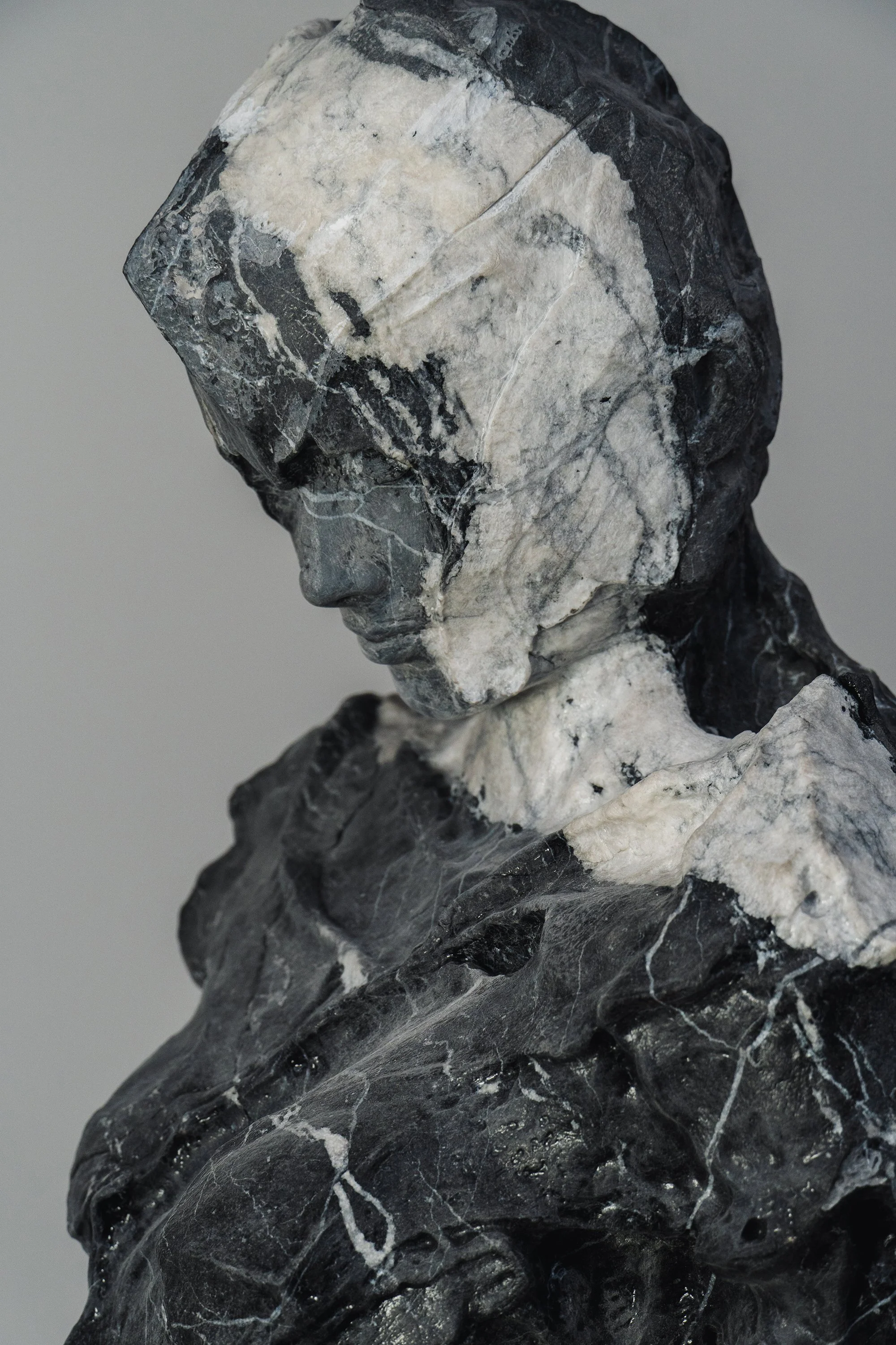 Scultura di busto femminile in marmo, caratterizzata da superfici materiche e venature naturali della pietra.