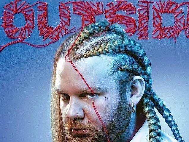 Ritratto del rapper Nitro con treccine dai colori naturali e trucco artistico, con scritta rossa all'origine composta da fili di corda. Cover dell'album Outsider.