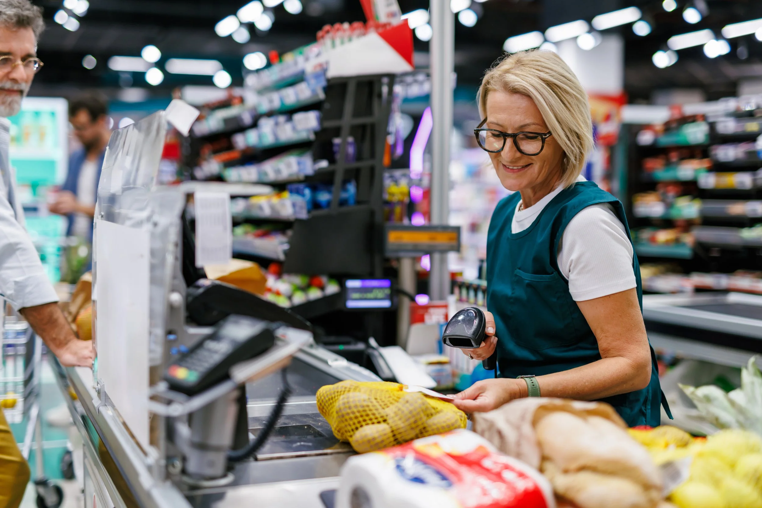 Image of a woman behind the checkout of an independent grocery store for who we work with retail