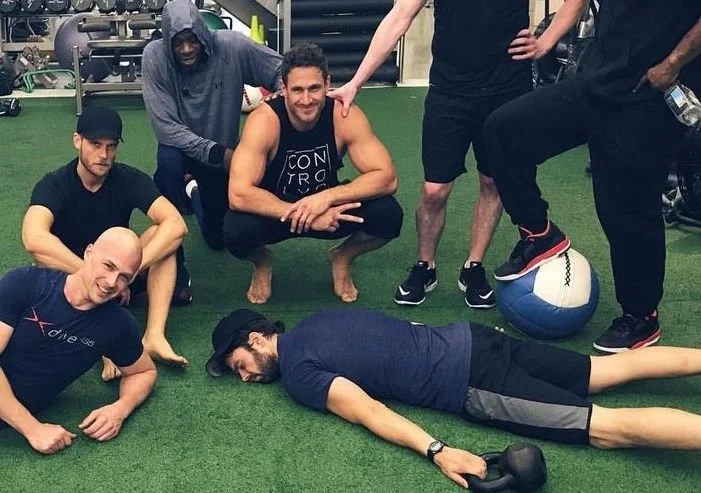 7 people resting on the gym floor after a workout