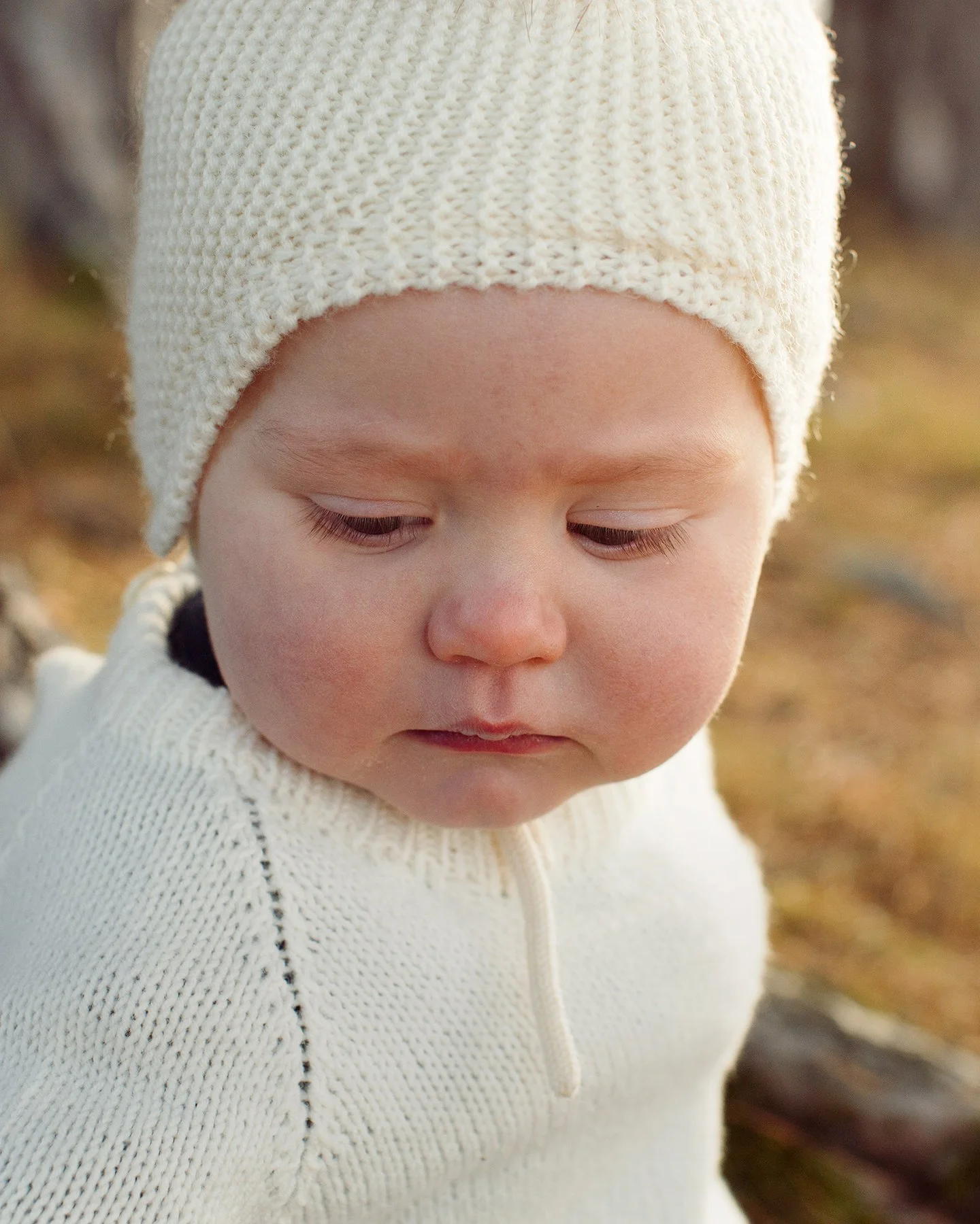 Barnefotografering om høsten. Et barn kikker forsiktig ned mot bakken.