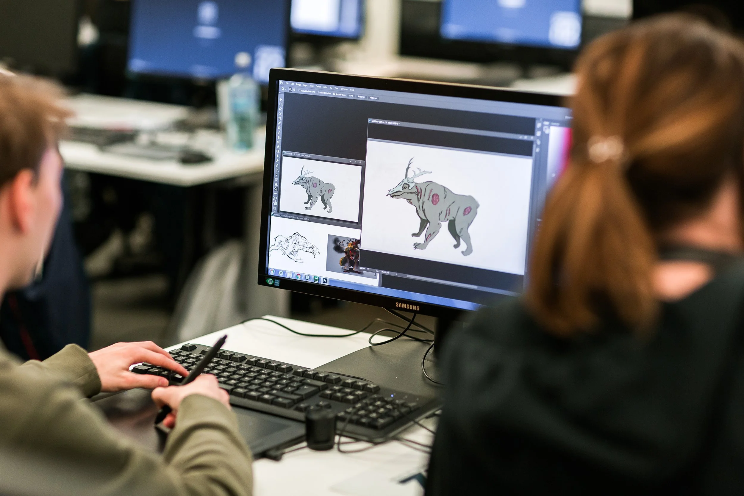 Reportasjebilde av student som jobber med en digital skisse av et monster på dataskjermen.