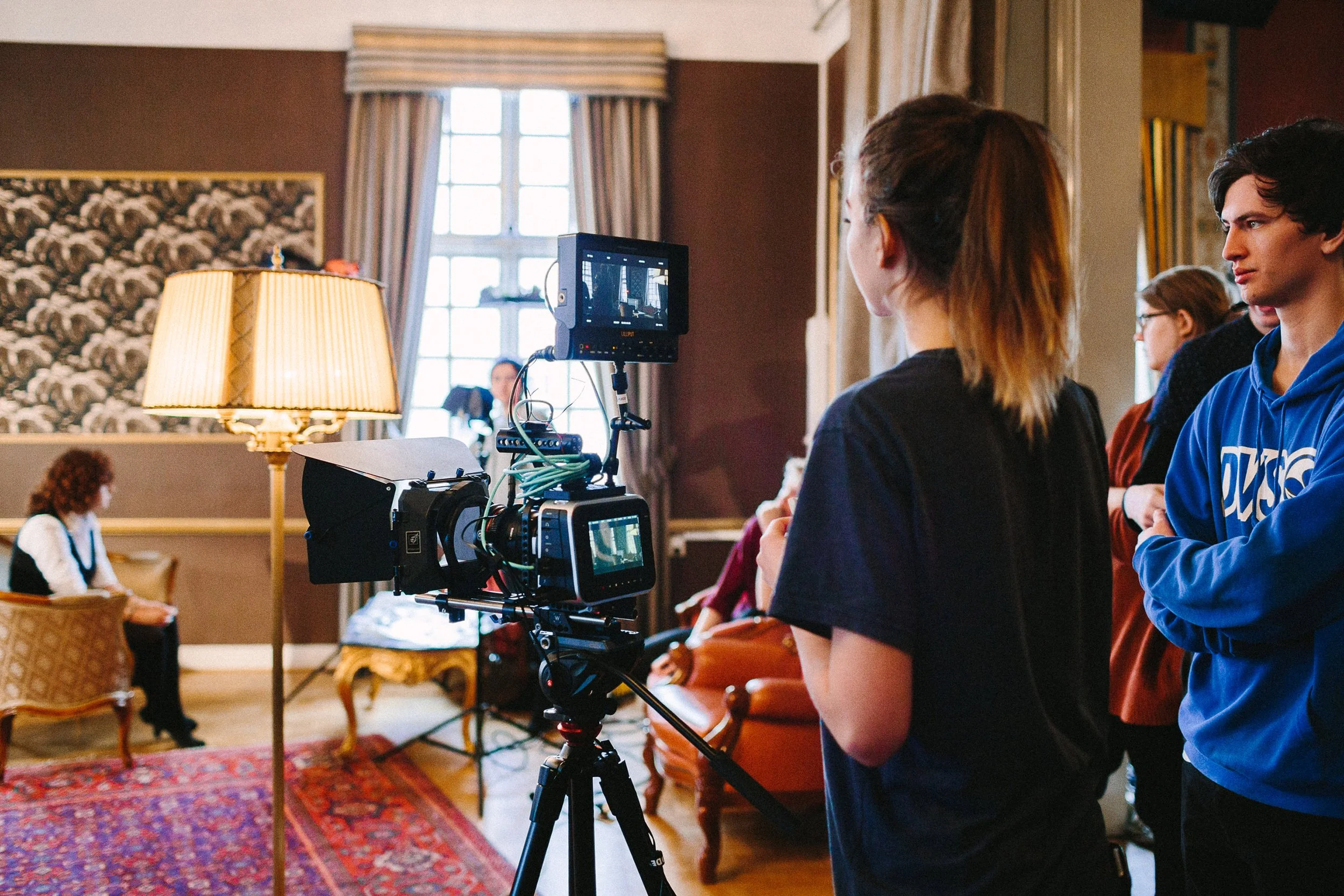 Opptaksdag på location. Studenter samarbeider med å stille inn bildet på kamera.