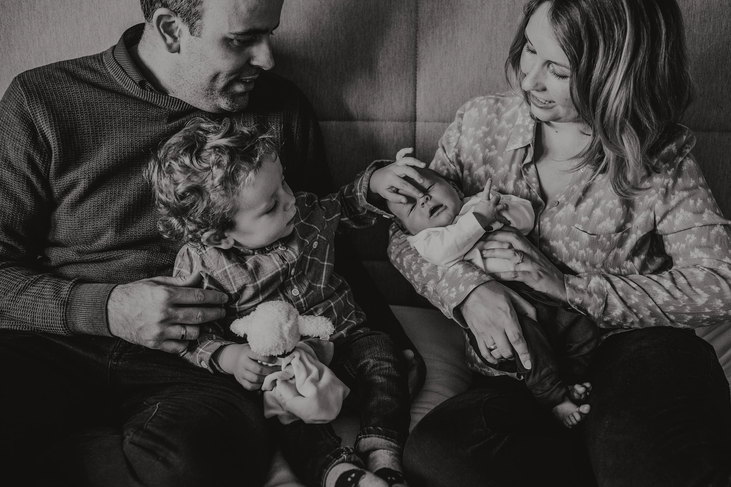 Nyfødtfotografering med hele familien hjemme. Storebror hilser på den nye babyen.