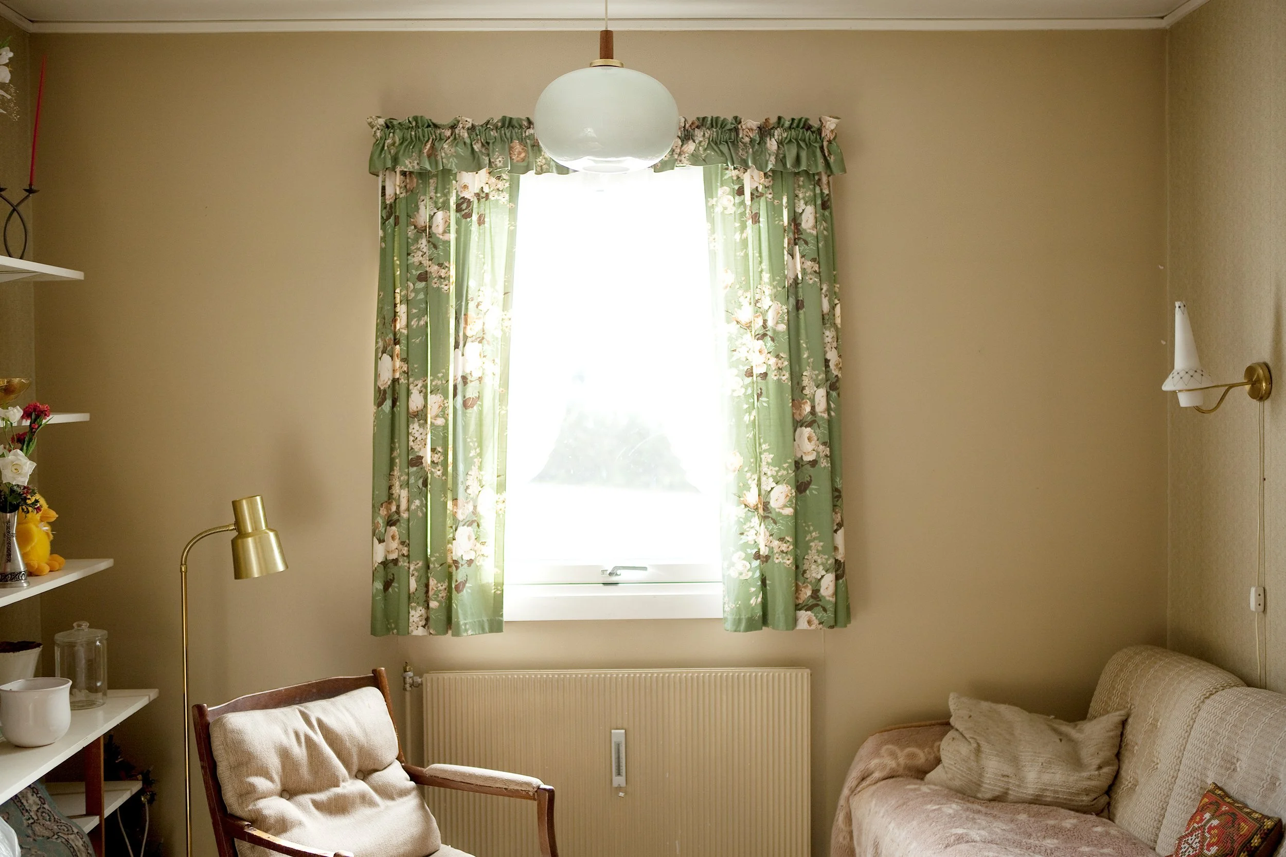 Utsnitt av rom, med et vindu i sentrum. Foran vinduet står en stol og leselampe.