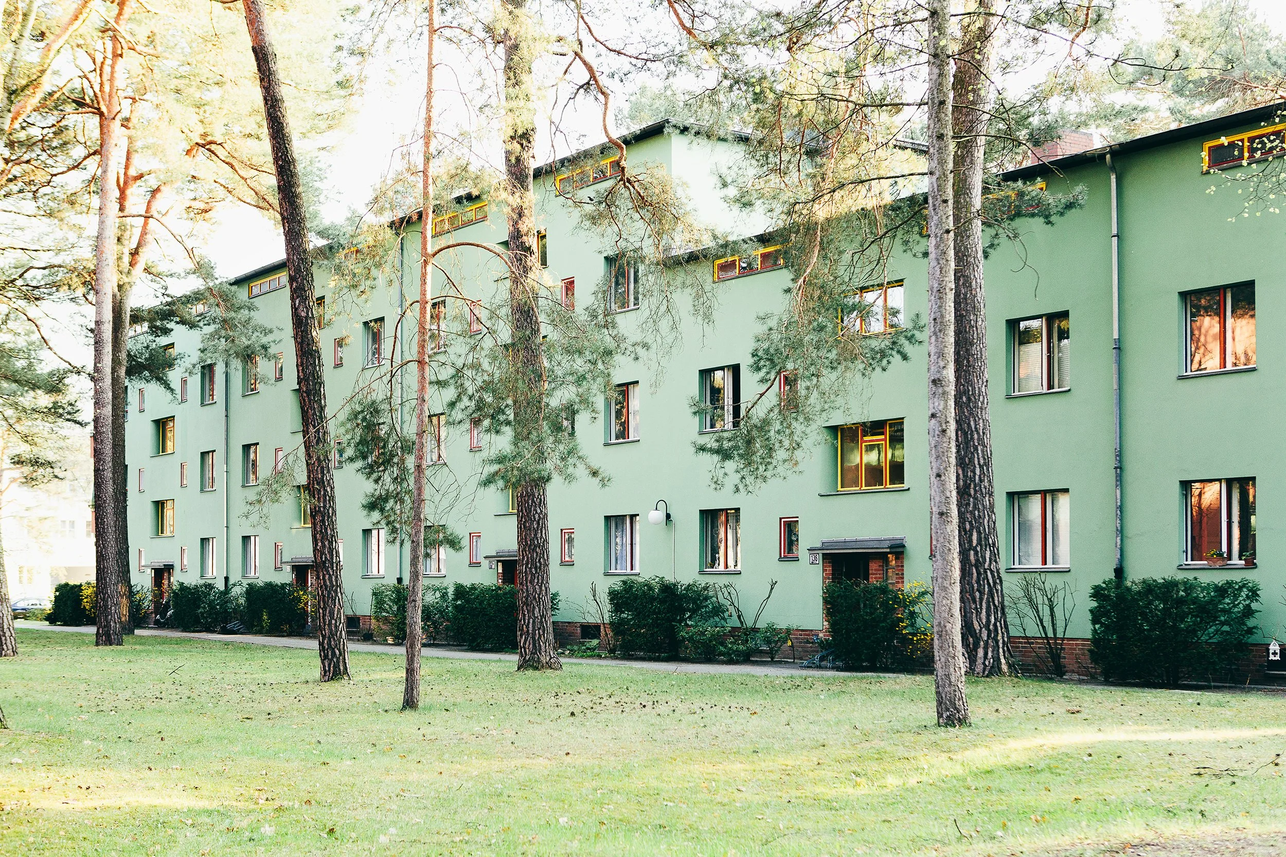 Boligfelt i Onkel Toms Hütte i Berlin, tegnet av arkitekt Bruno Taut. Grønn boligblokk omsluttet av høye trær.