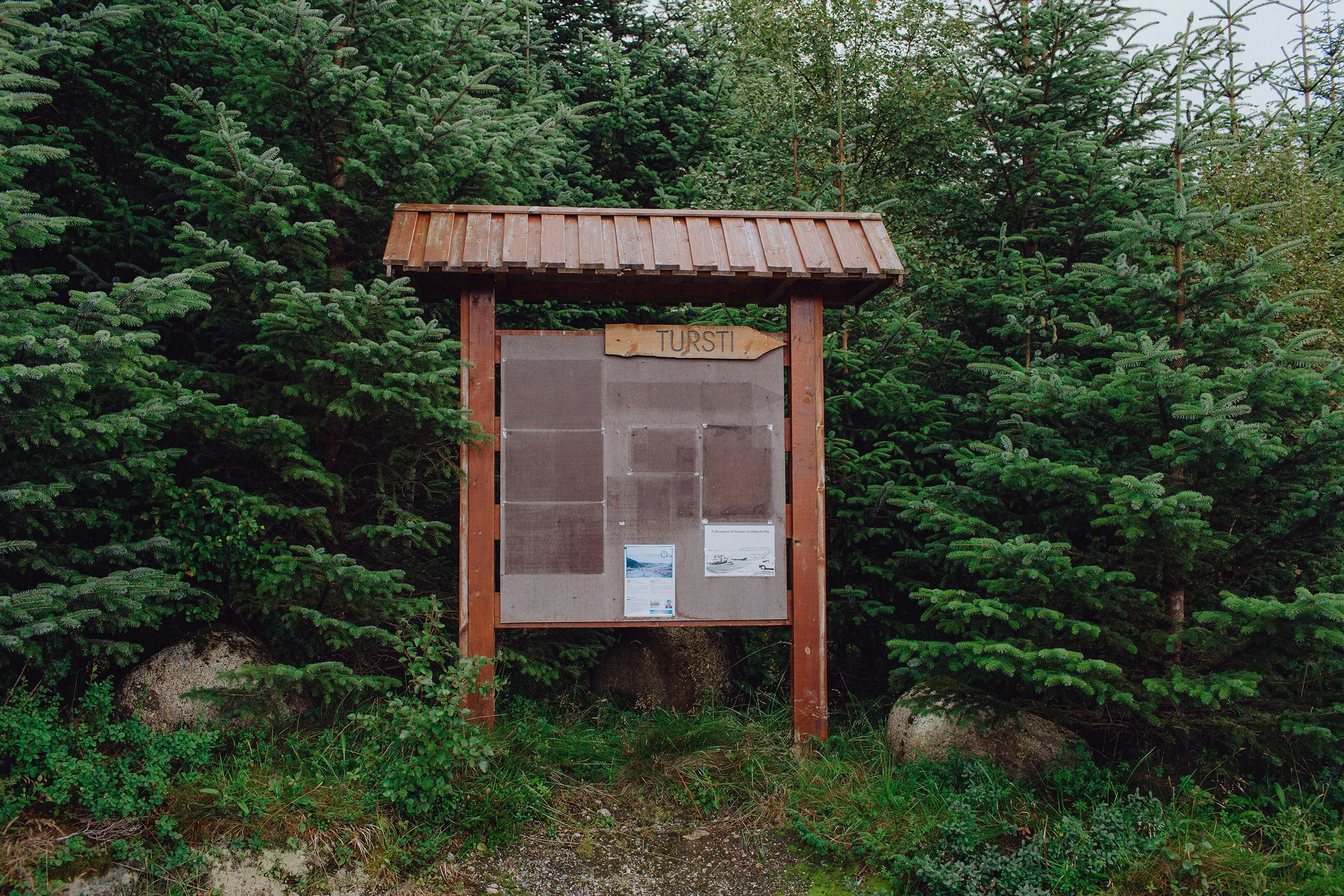 Skilt med turistinformasjon i skogen.