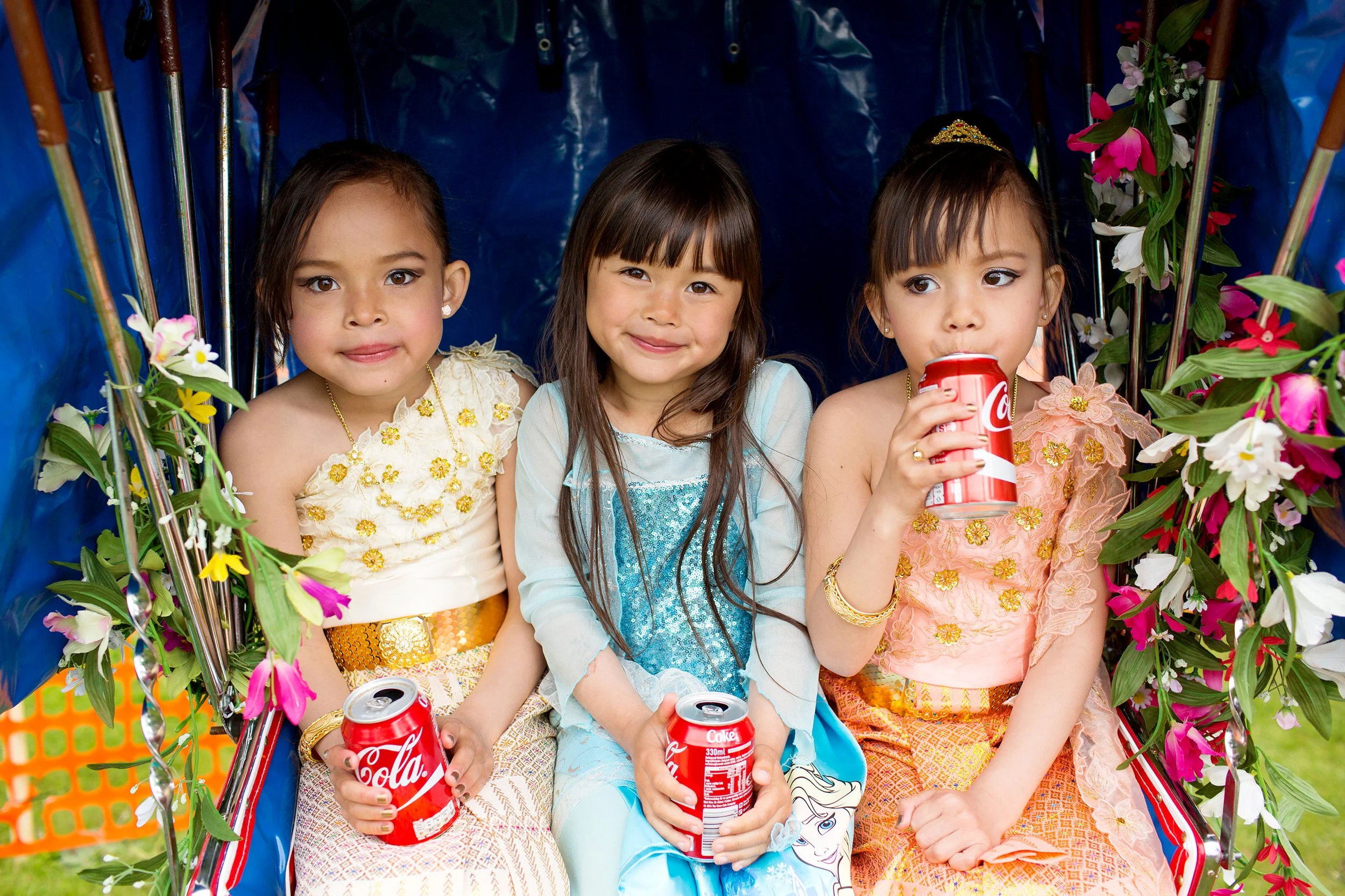 Stoppested Verden internasjonal barnefestival. Tre små jenter kledd i festdrakter slapper av med drikke