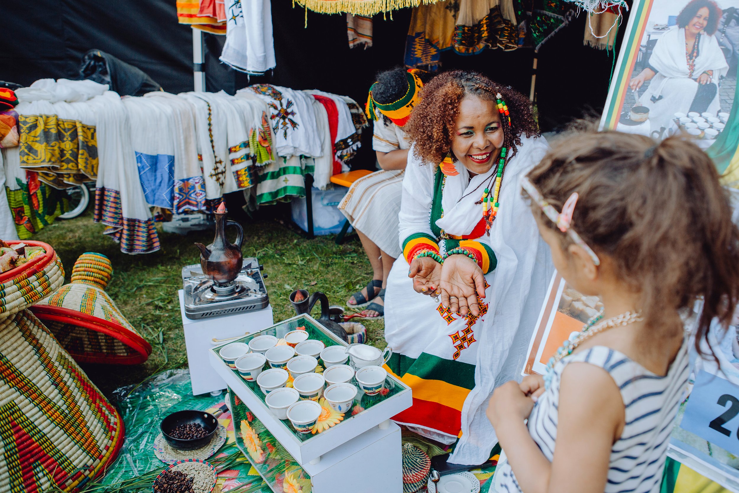 Stoppested Verden internasjonal barnefestival. Jente snakker med kvinne som serverer kaffe.