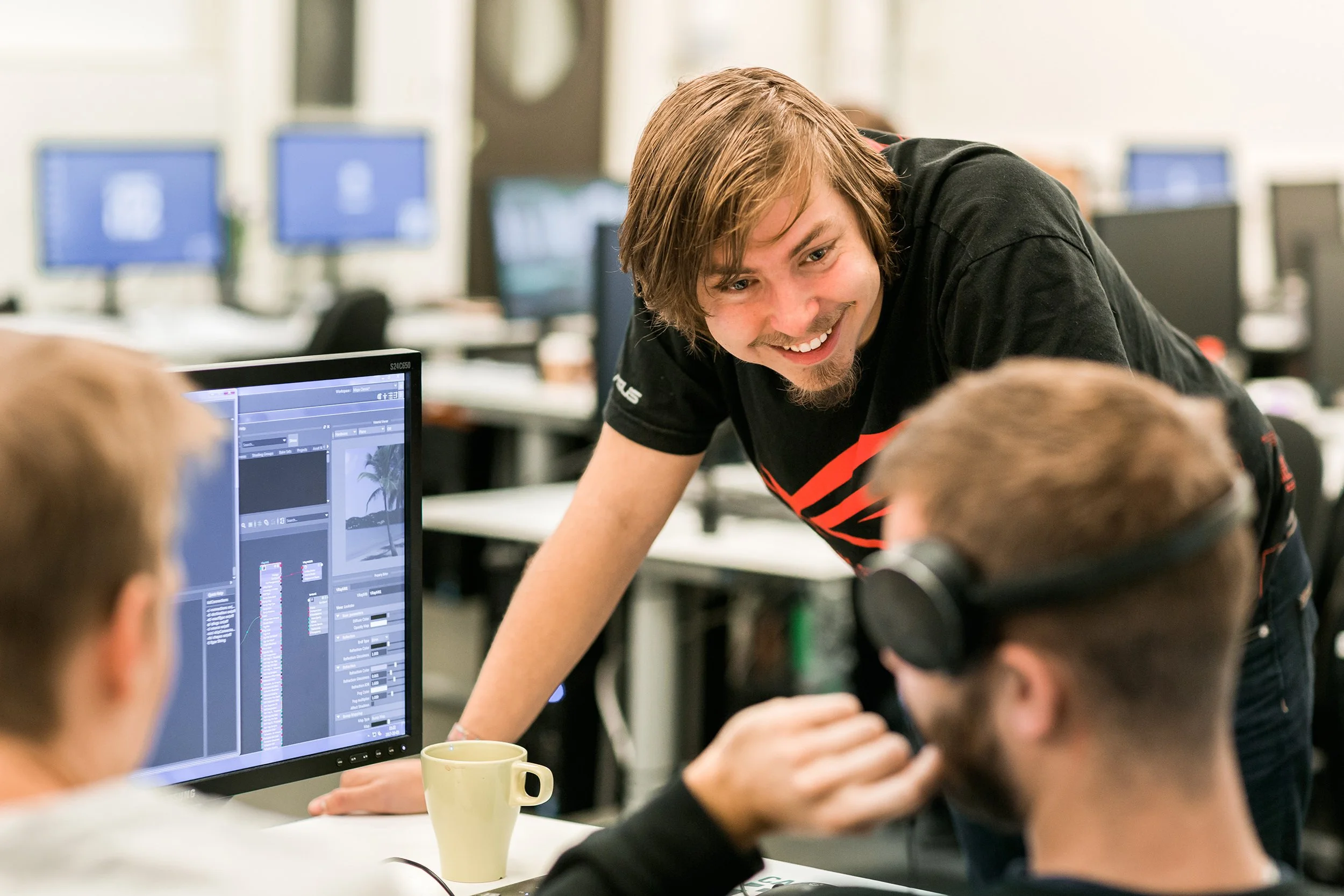 Miljøbilde av tre studenter som samtaler om arbeidet på datamaskinen