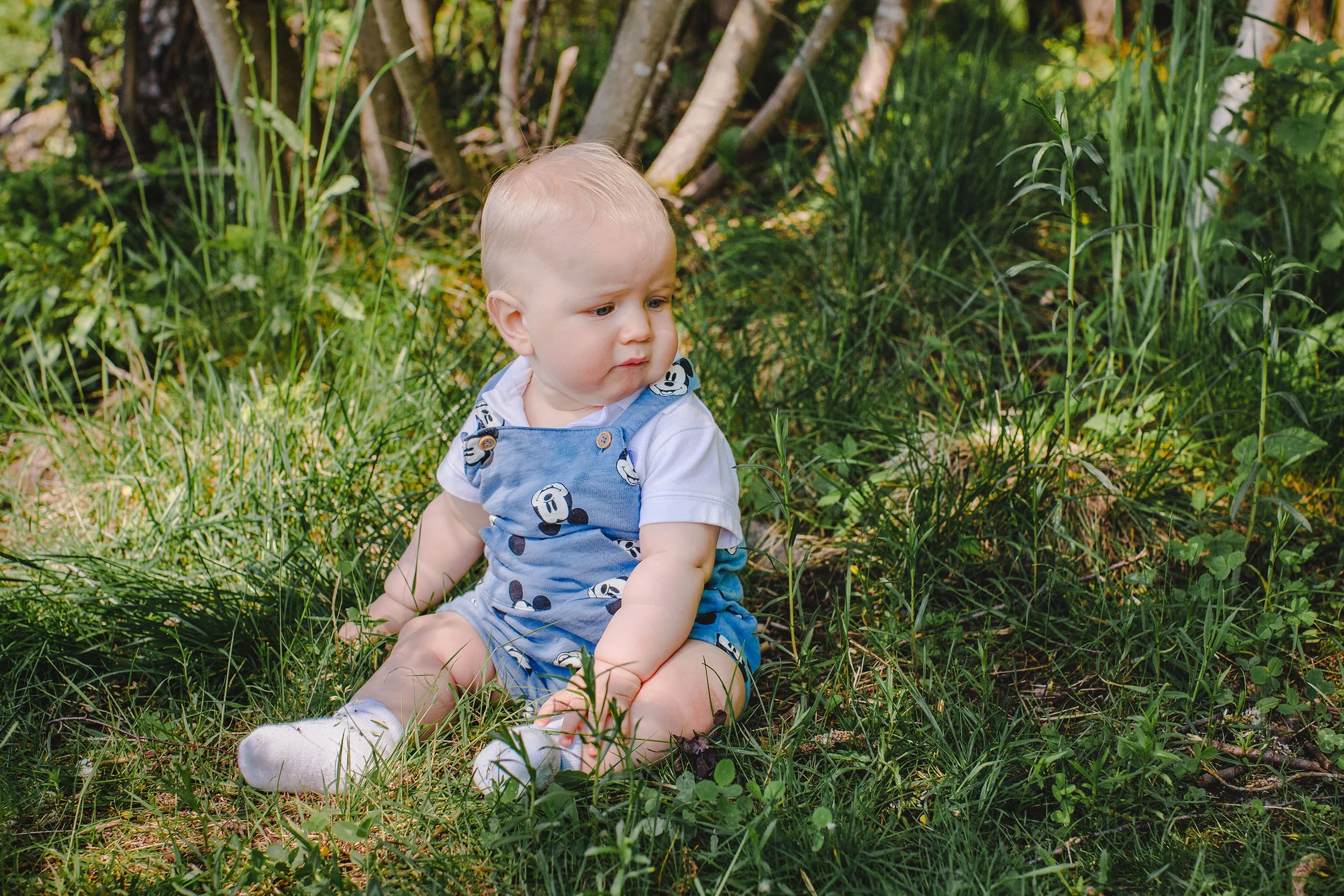 Barnefotografering i Hamar: Baby sittende på gresset i skogen