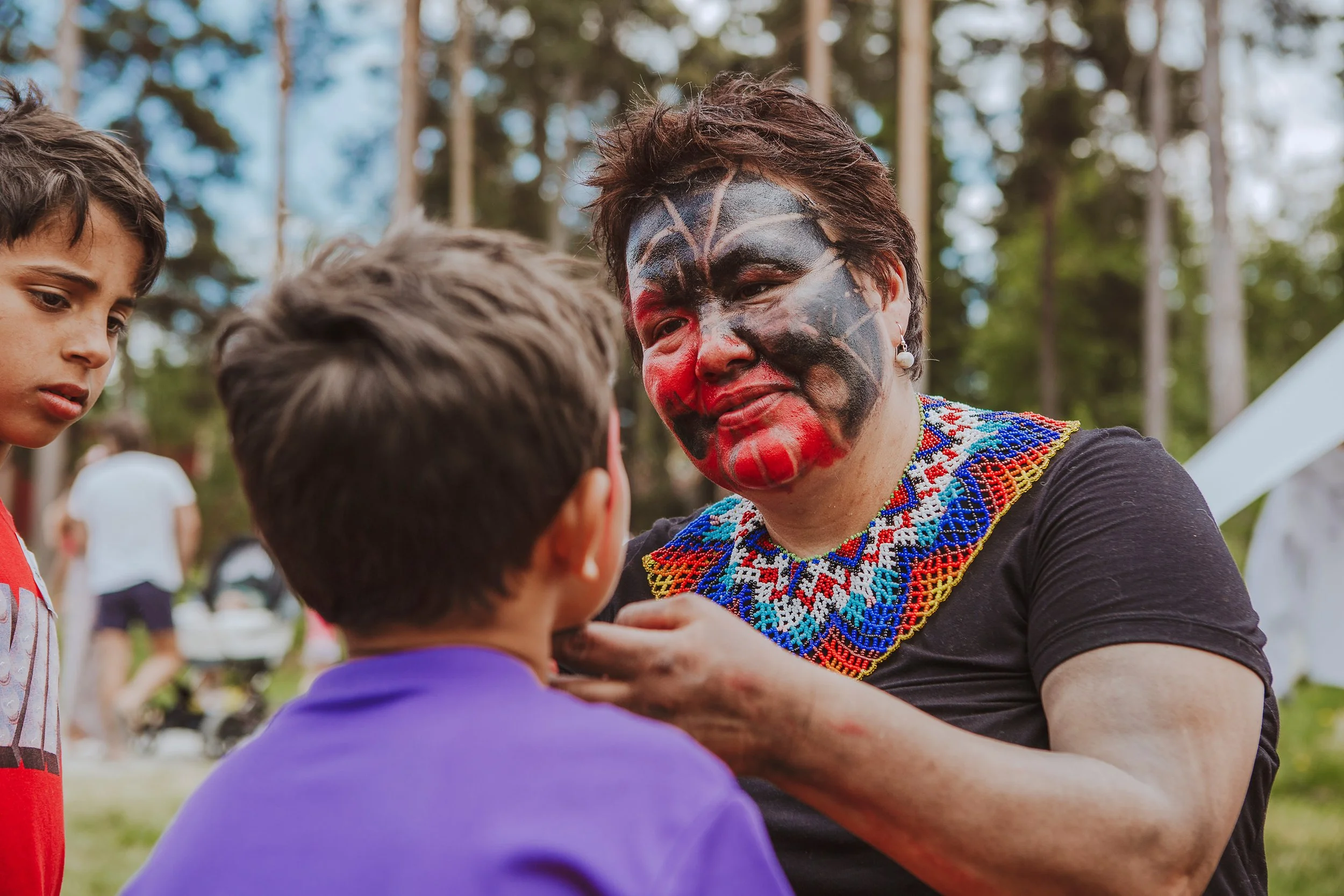 Stoppested Verden internasjonal barnefestival. Kvinne med ansiktsmaling maler ansiktet til en gutt.
