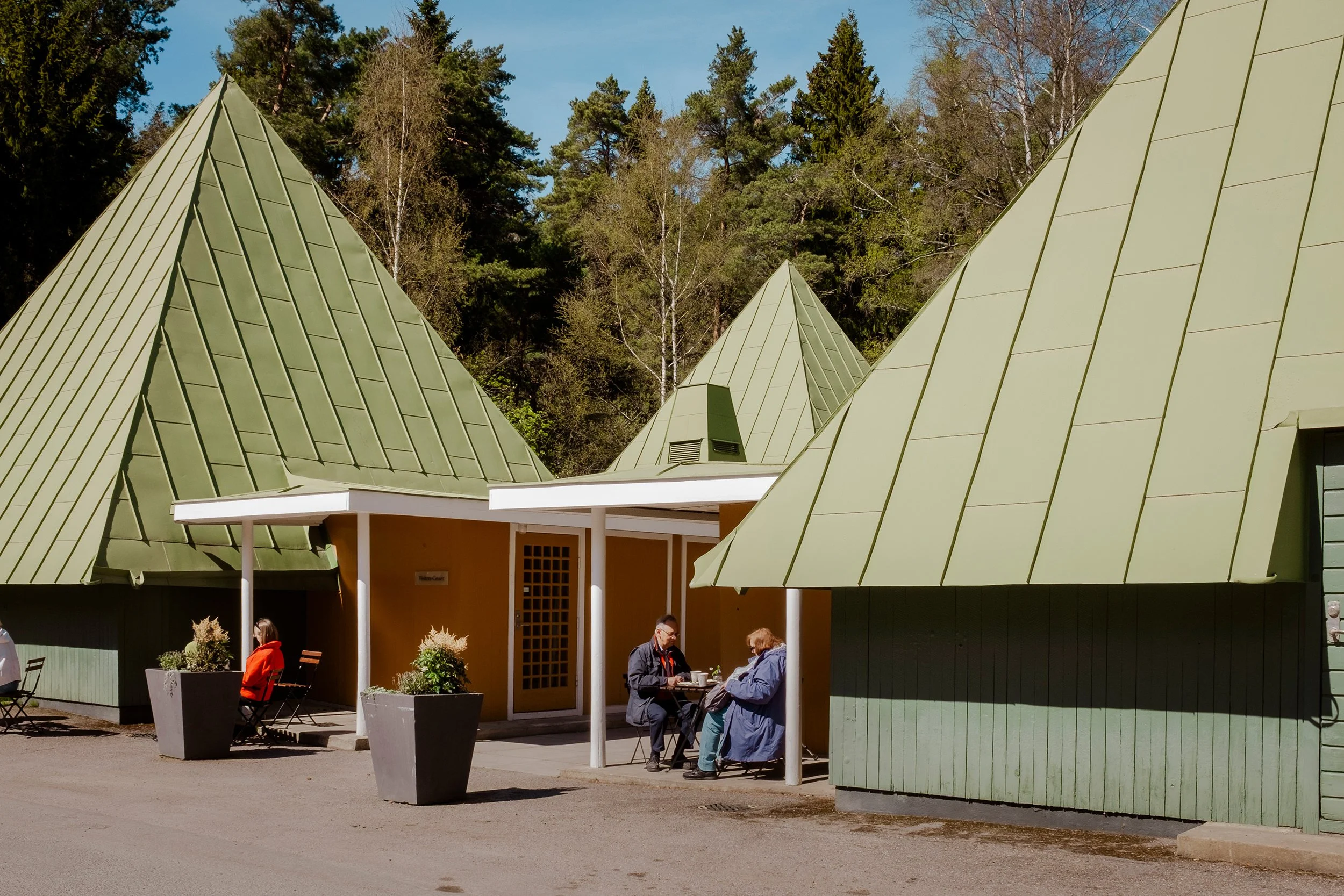 En mann og en dame spiser lunsj mellom grønne trekanthus.