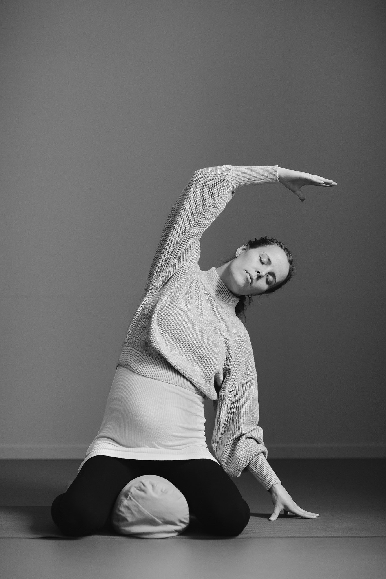 Profesjonelt bilde av gravid kvinne i yoga positur på gulvet.